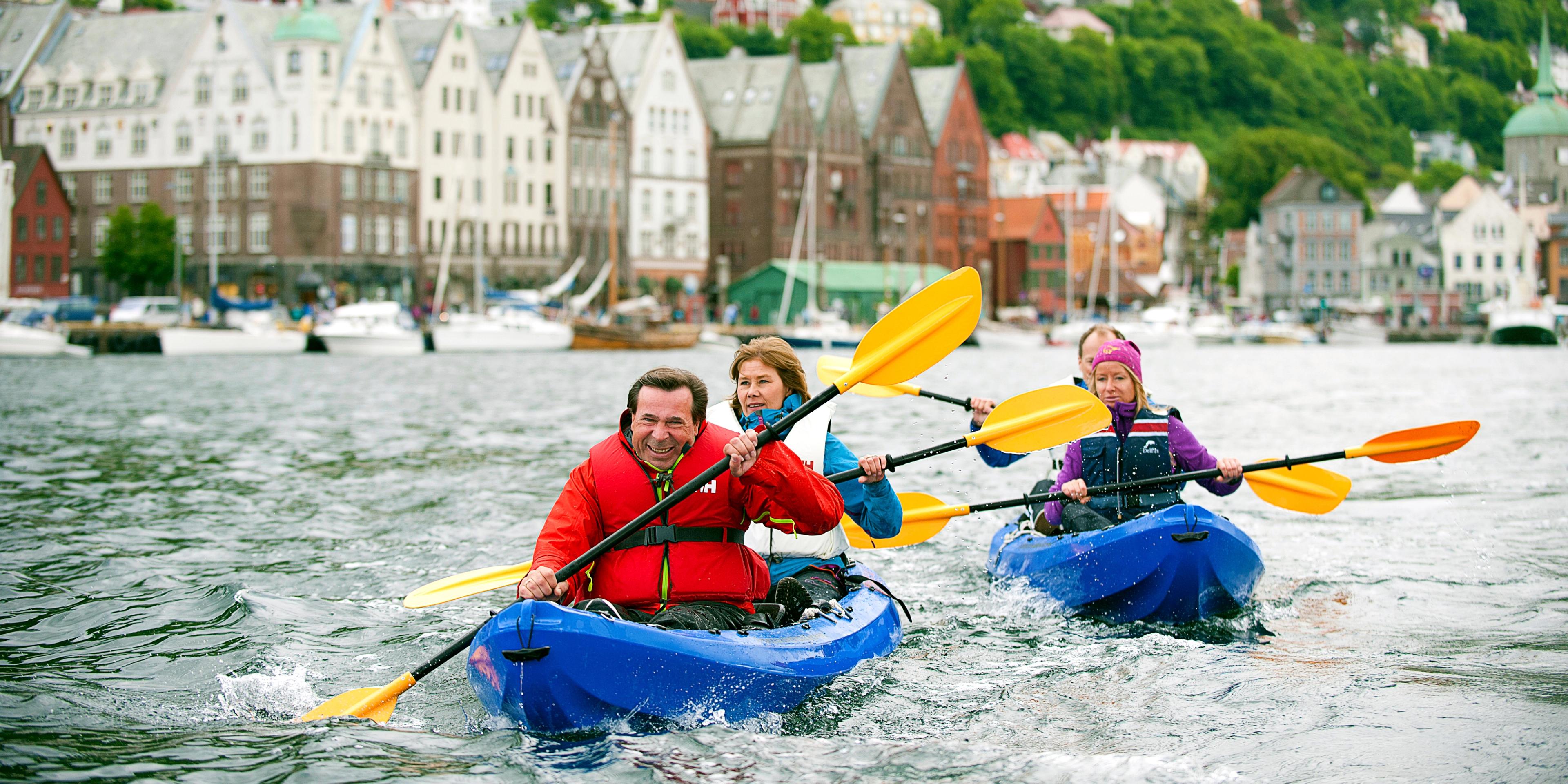 Three people in kayaks in Bergen harbour, Norway