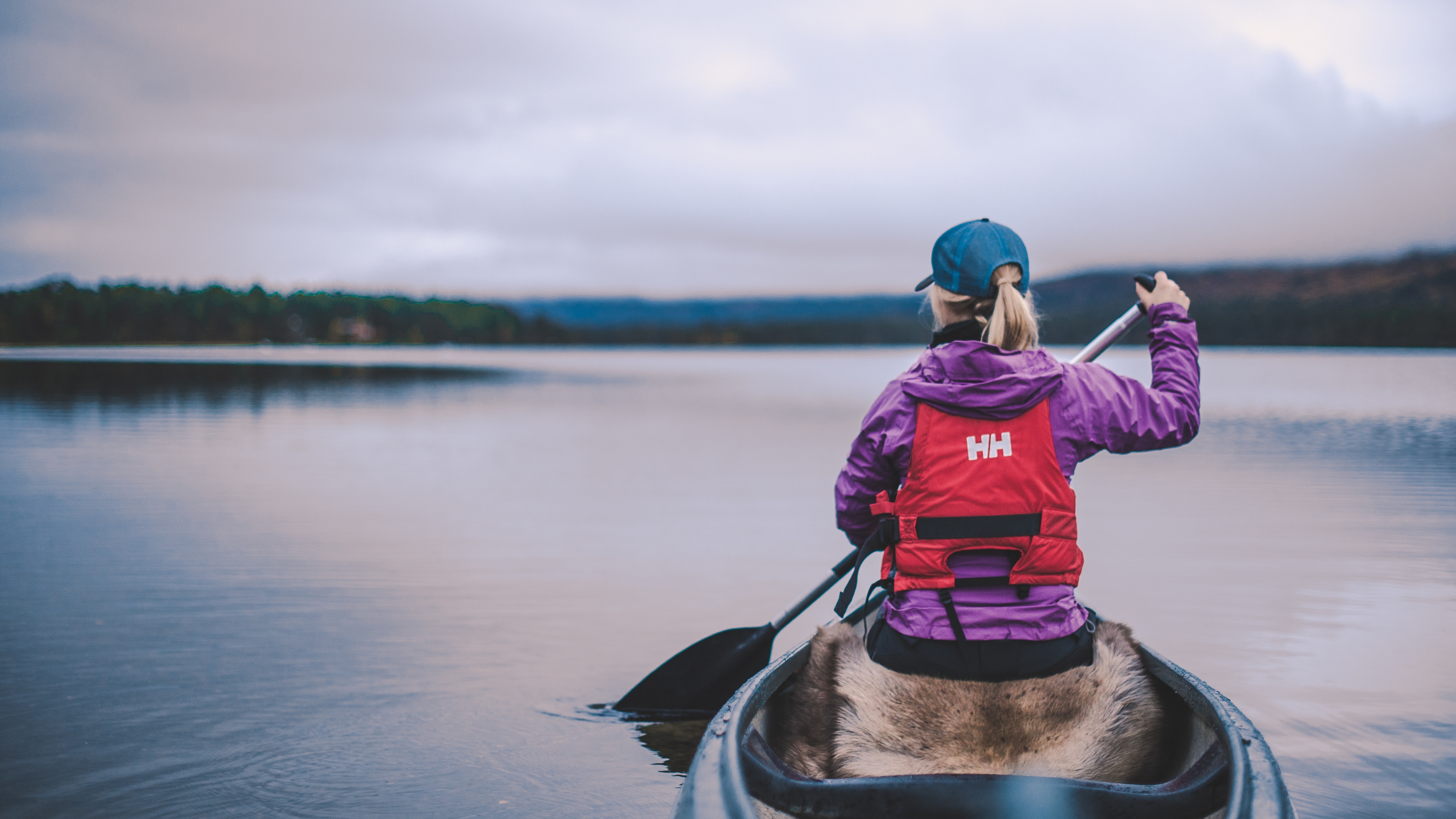A woman is paddling in the Lesjaskogvatnet lake in Gudbrandsdalen, Eastern Norway