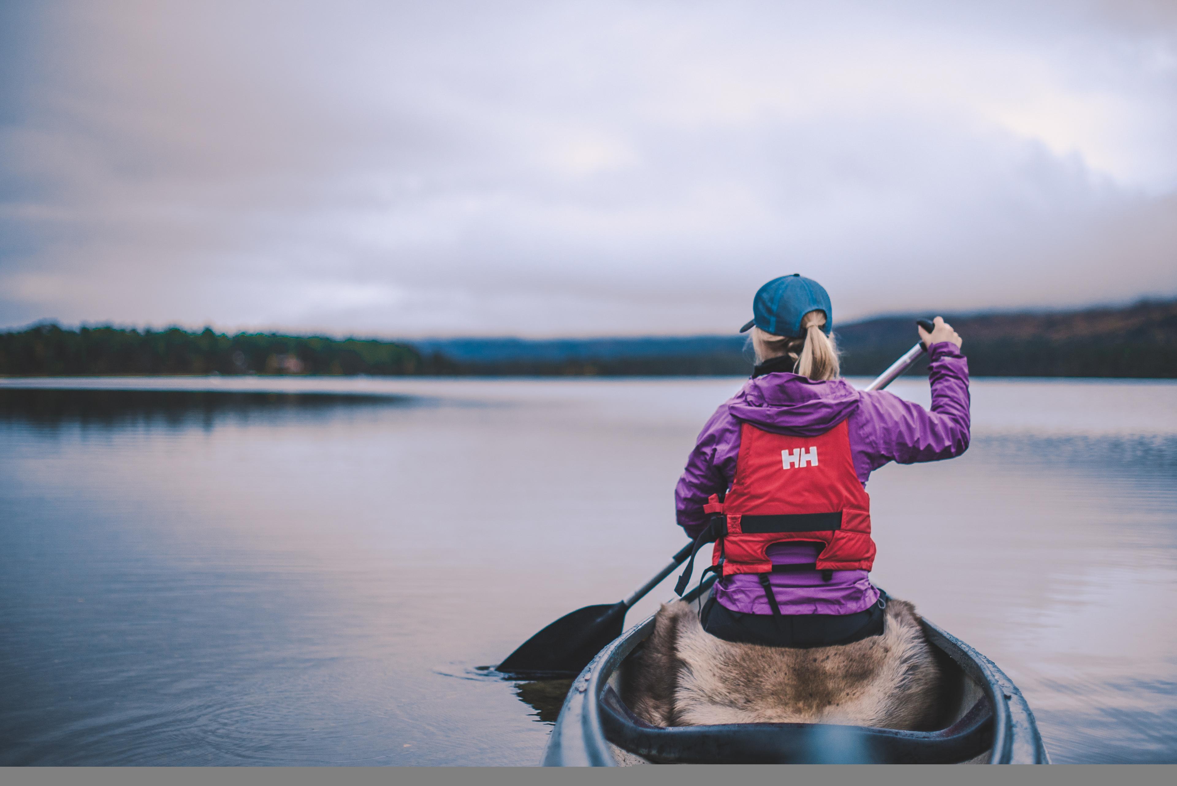 A woman is paddling in the Lesjaskogvatnet lake in Gudbrandsdalen, Eastern Norway