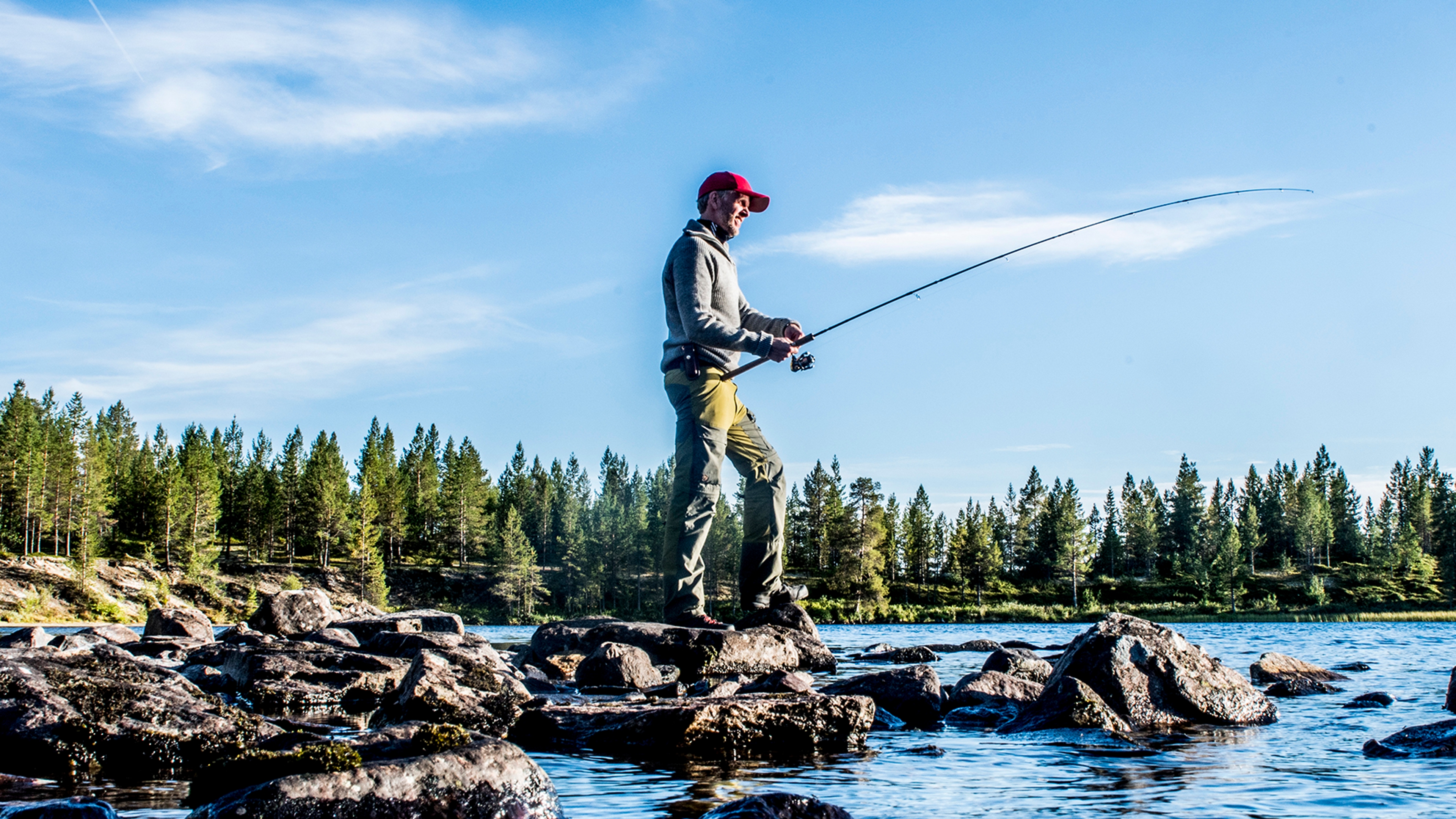 A man freshwater fishing on a sunny day in Femundsmarka National Park in Eastern Norway