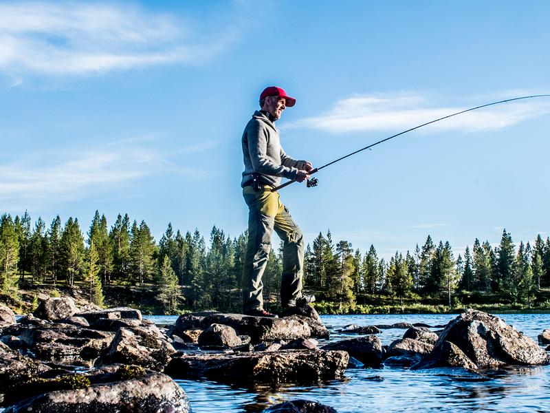 A man freshwater fishing on a sunny day in Femundsmarka National Park in Eastern Norway