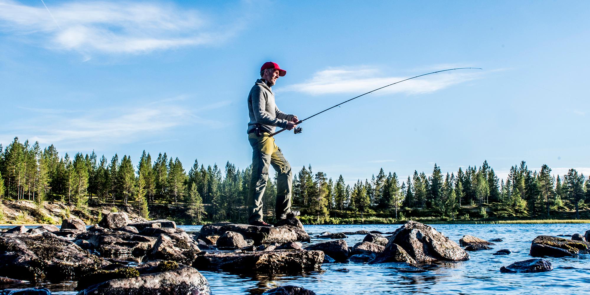 A man freshwater fishing on a sunny day in Femundsmarka National Park in Eastern Norway