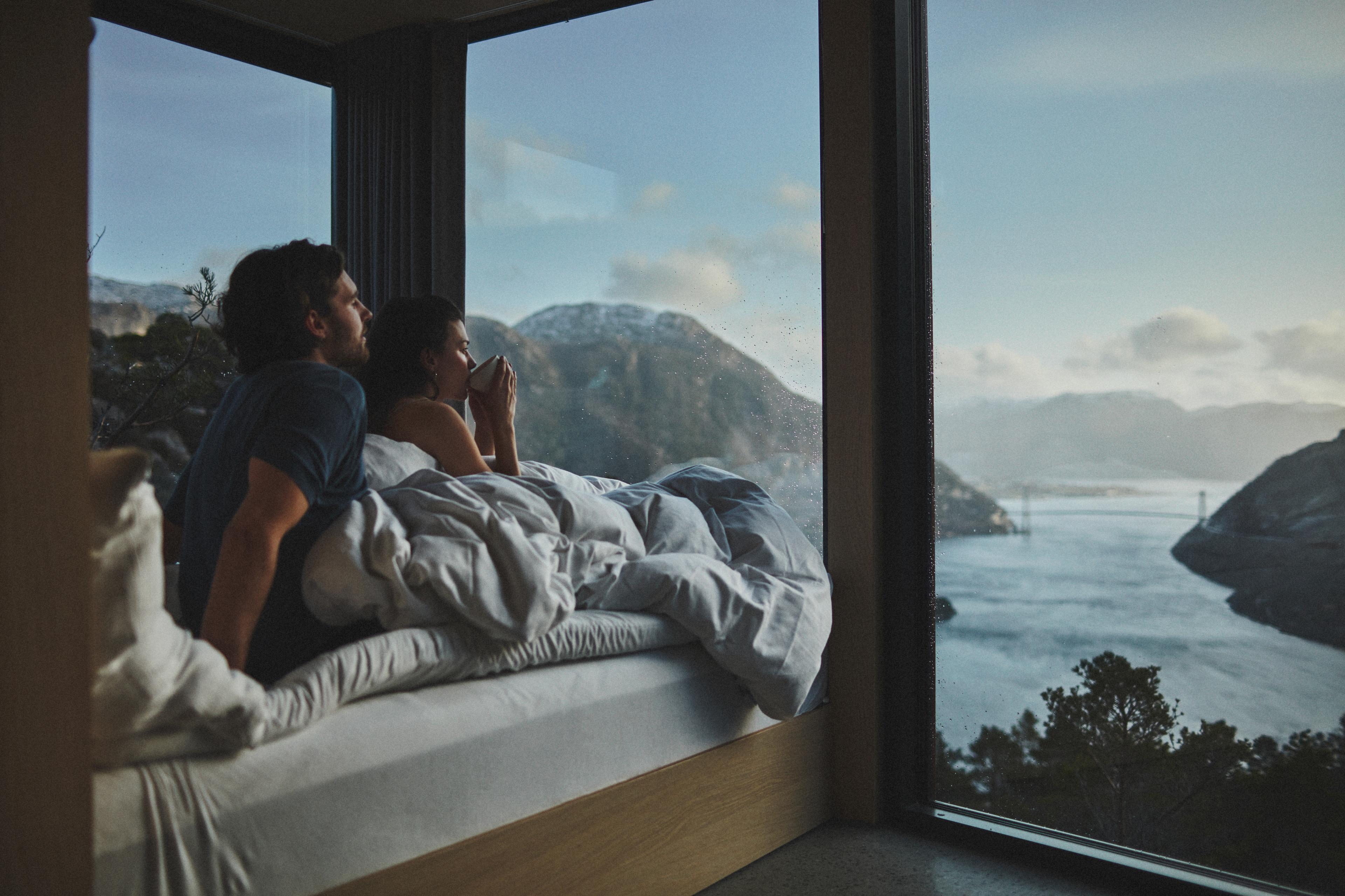 Couple in bed looking at the view over Lysefjorden in Rogaland, Fjord norway