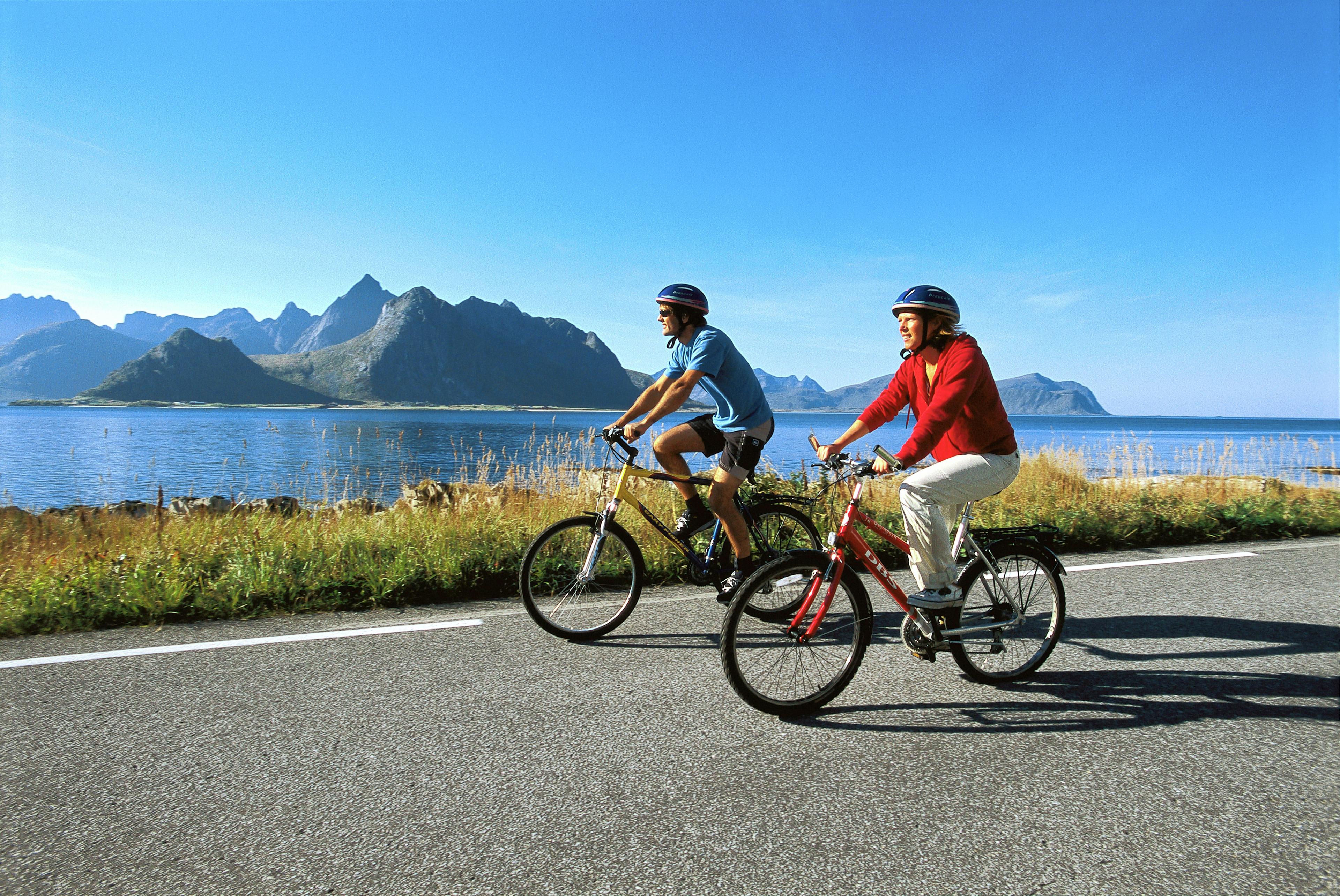 To personer cykler langs kysten på Lofoten i Nord-Norge