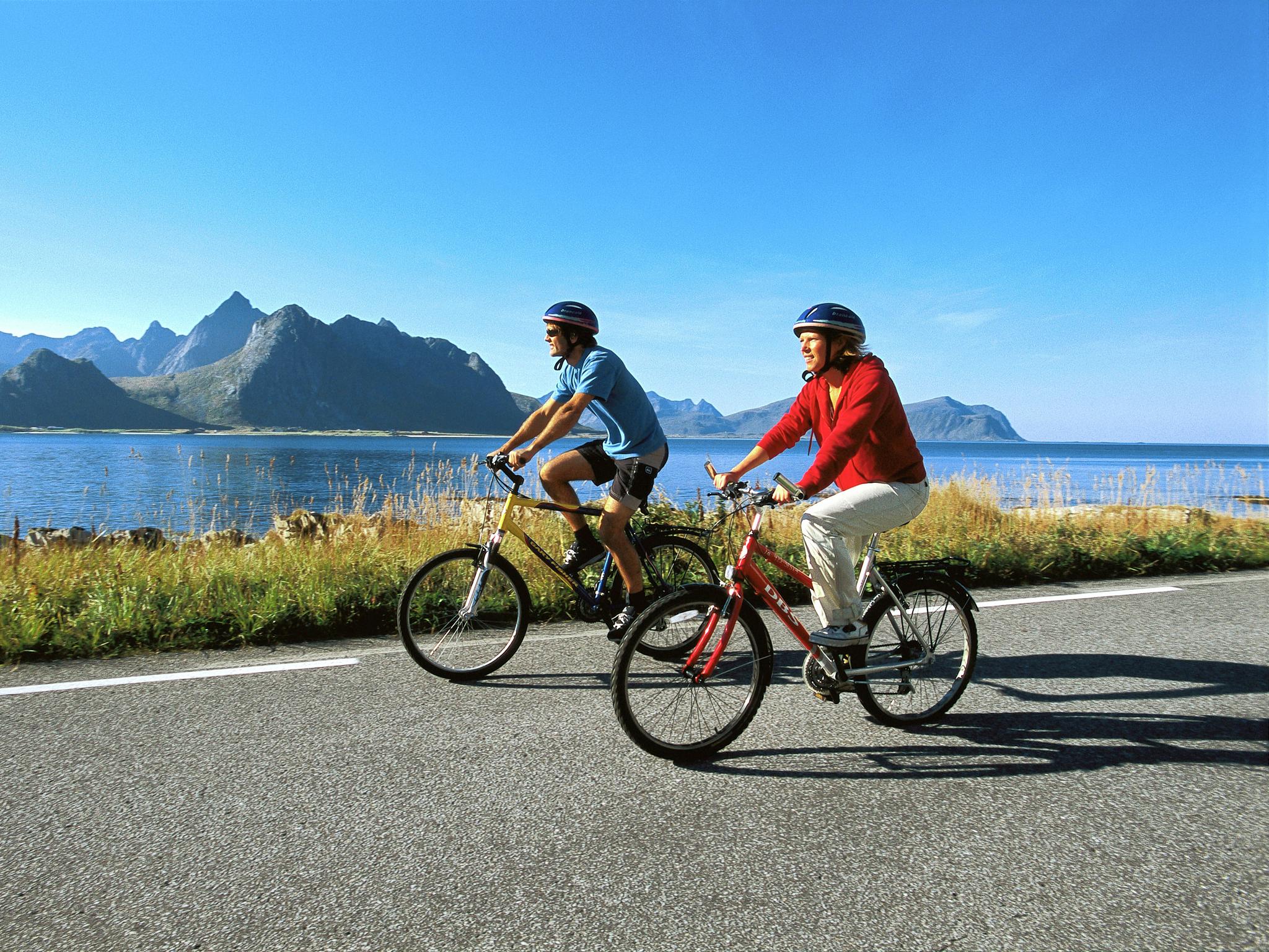 Two people cycling along the coast of Lofoten in Northern Norway