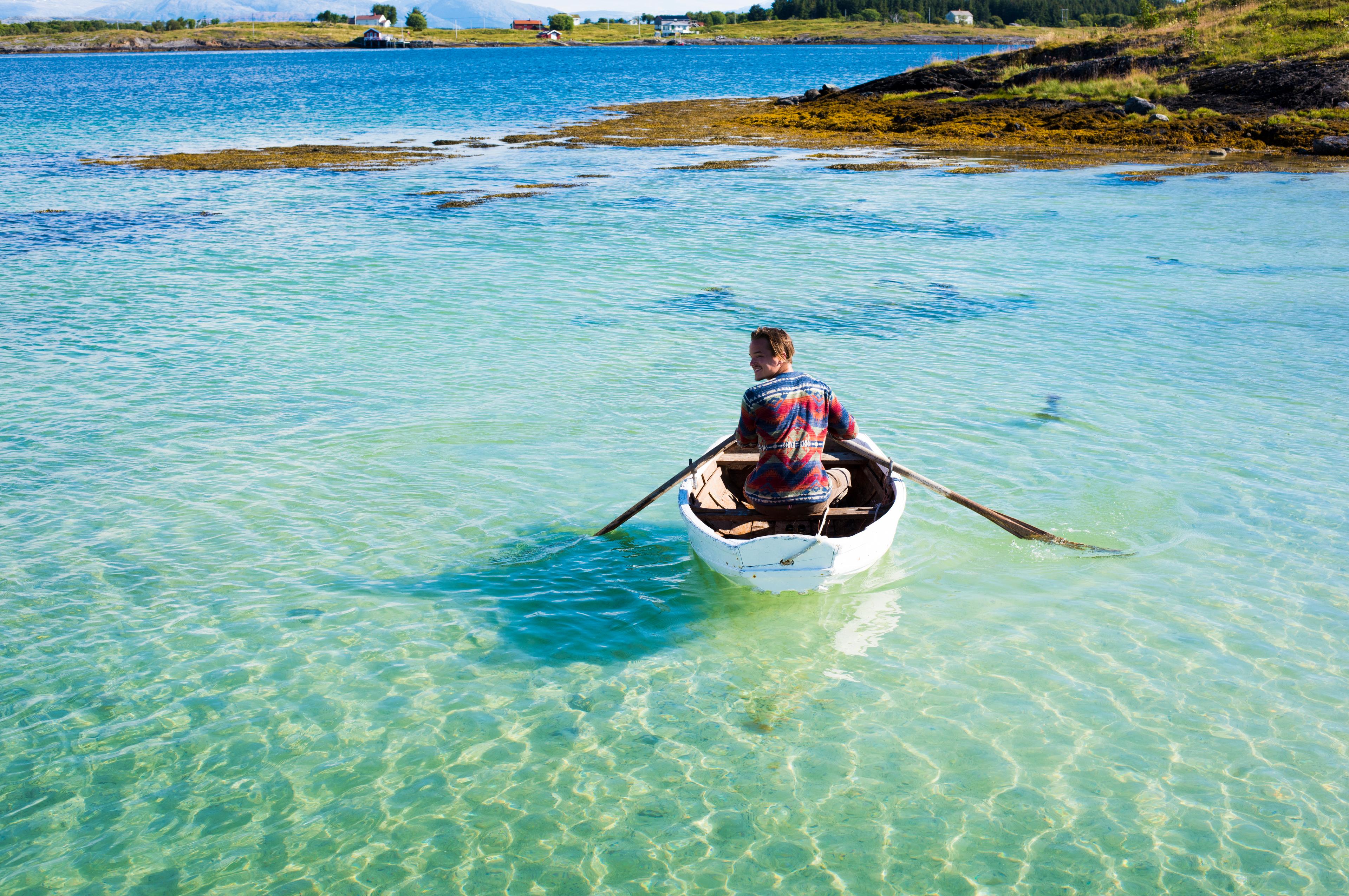 A person in a rowing boat in crystal clear water. Helgeland, Northern Norway.