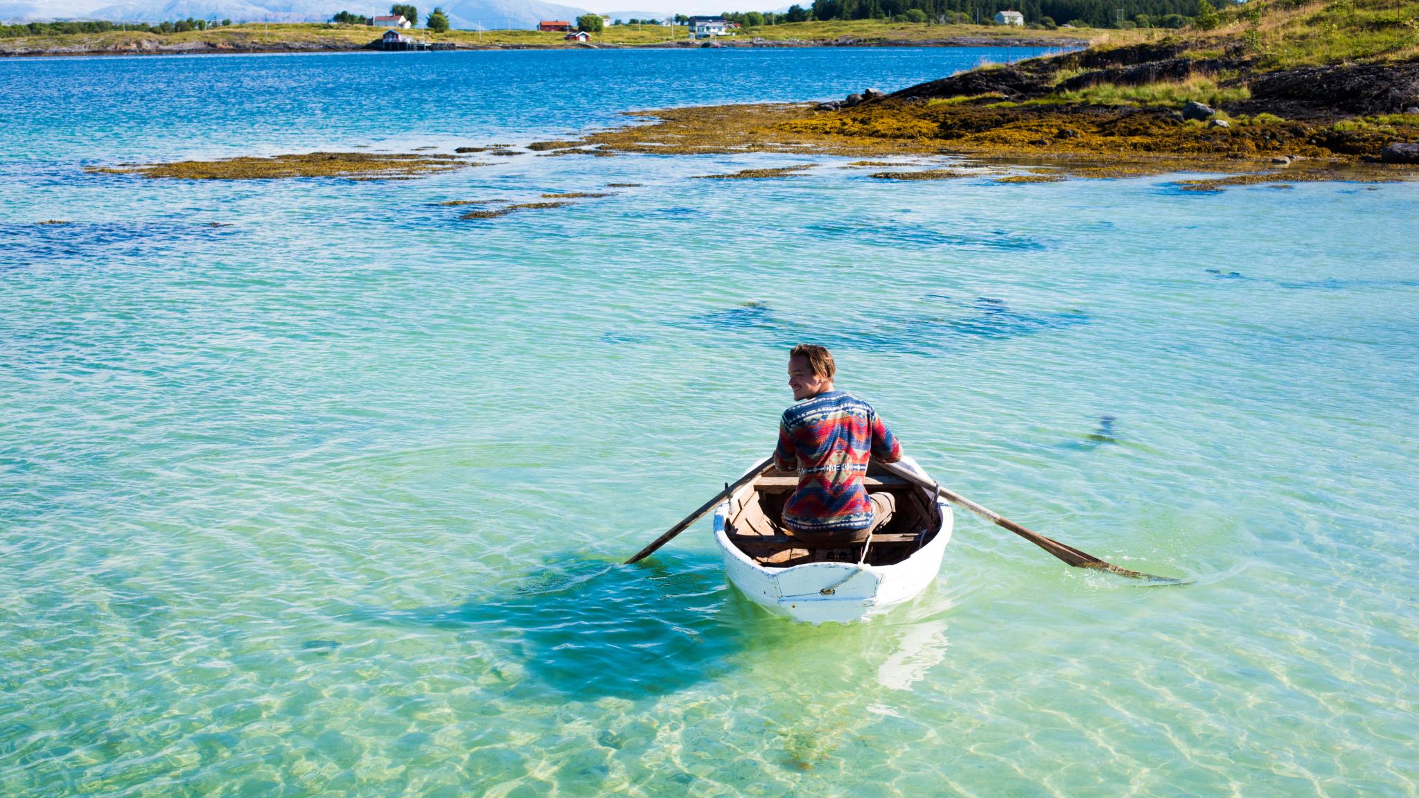 A person in a rowing boat in crystal clear water. Helgeland, Northern Norway.