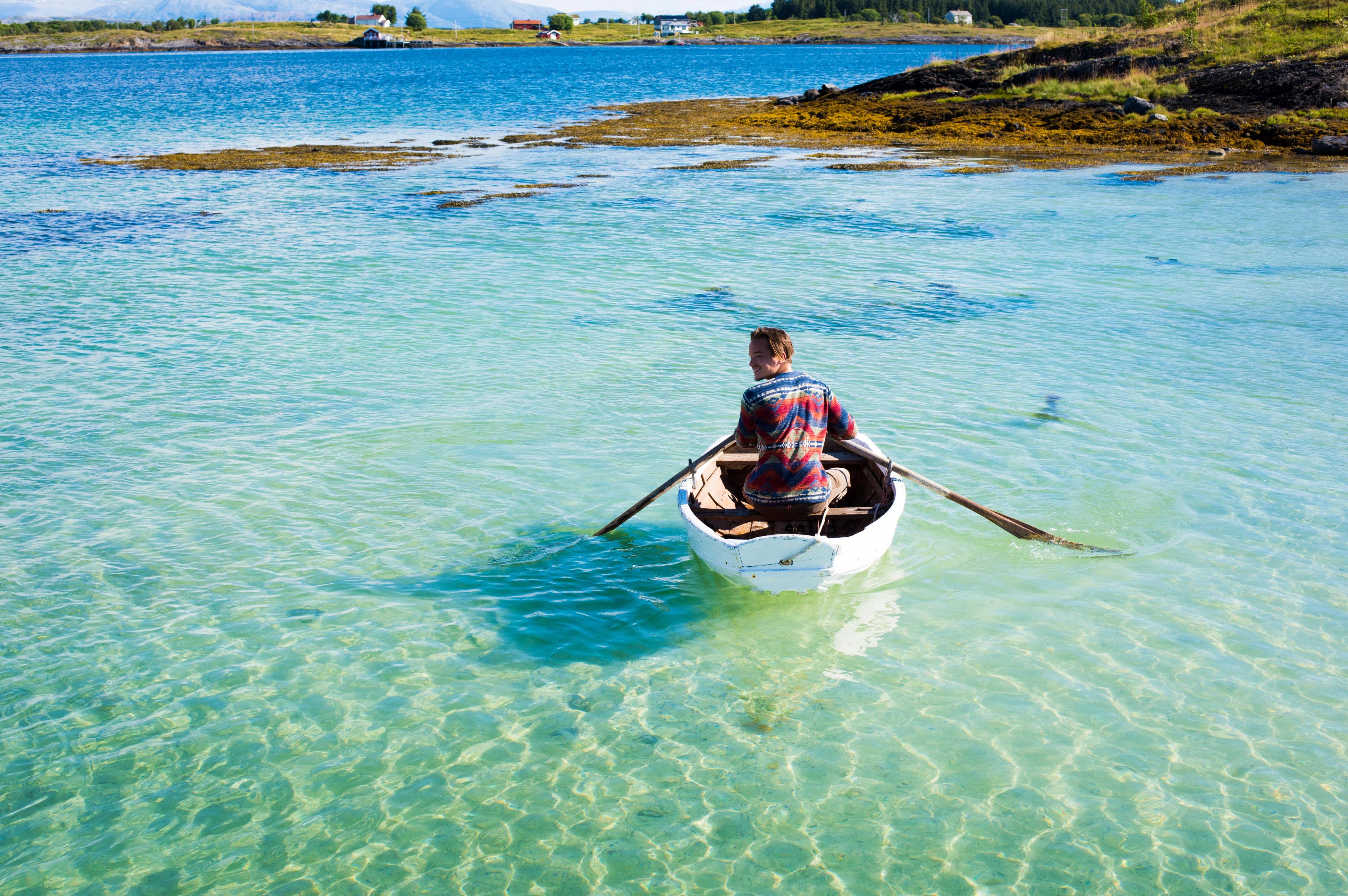 A person in a rowing boat in crystal clear water. Helgeland, Northern Norway.