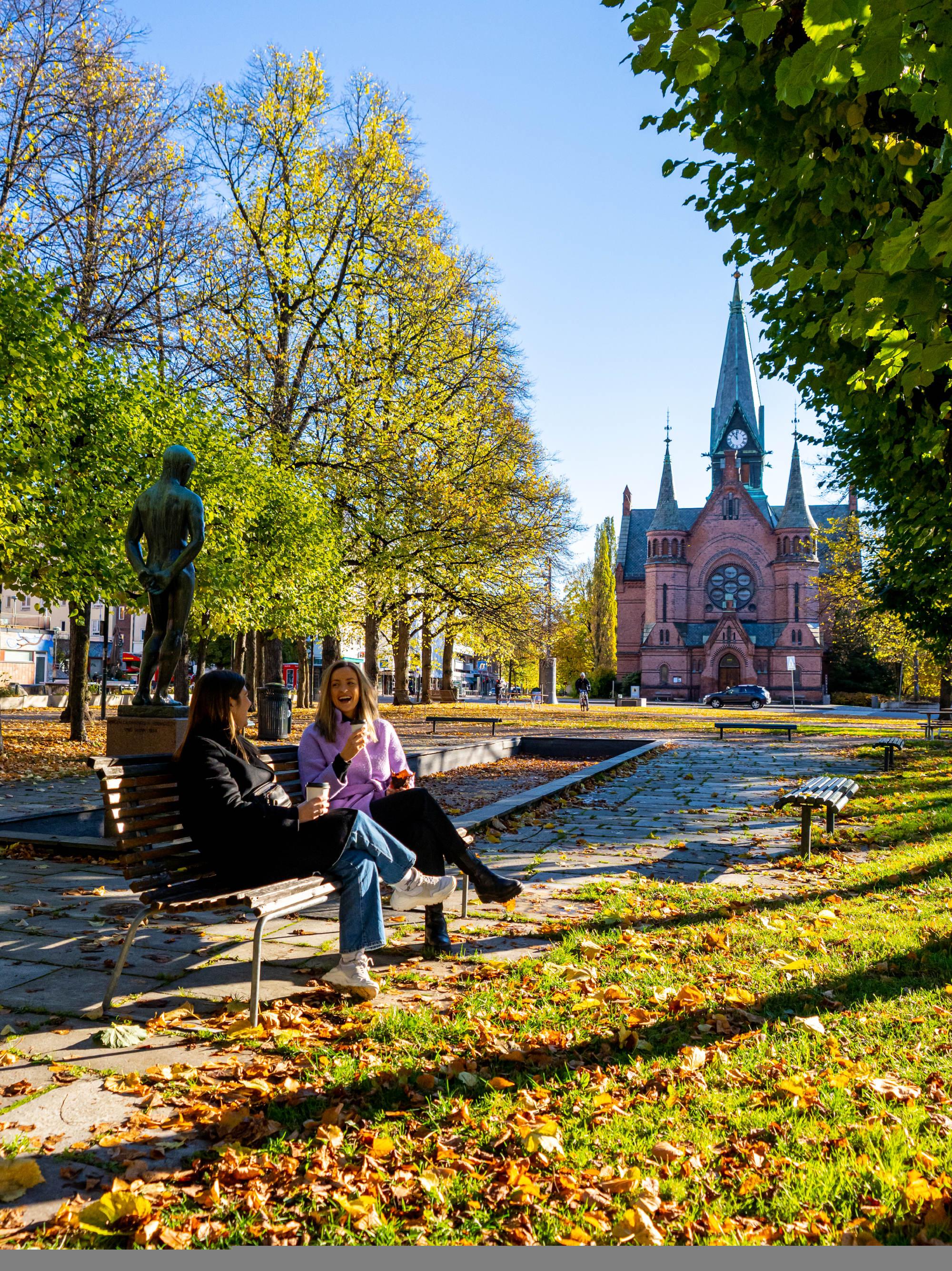 Two women drinking coffee at a bench at Sagene