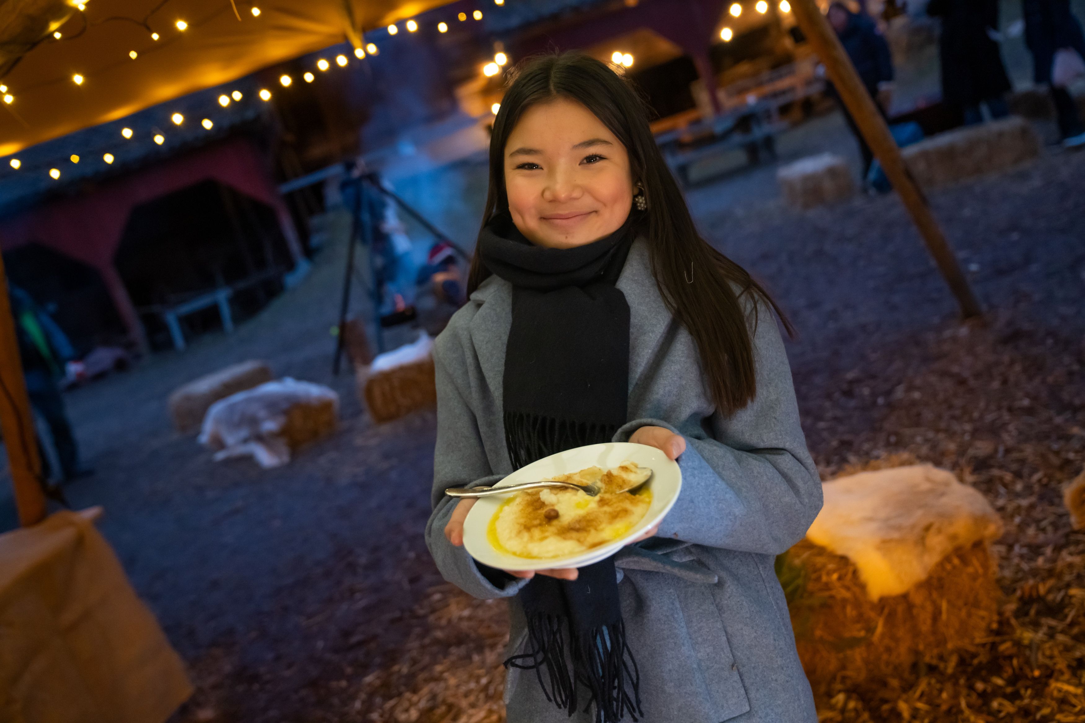 A girl is eating porridge at the Christmas market in Norsk Folkemuseum in Bygdøy, Eastern Norway