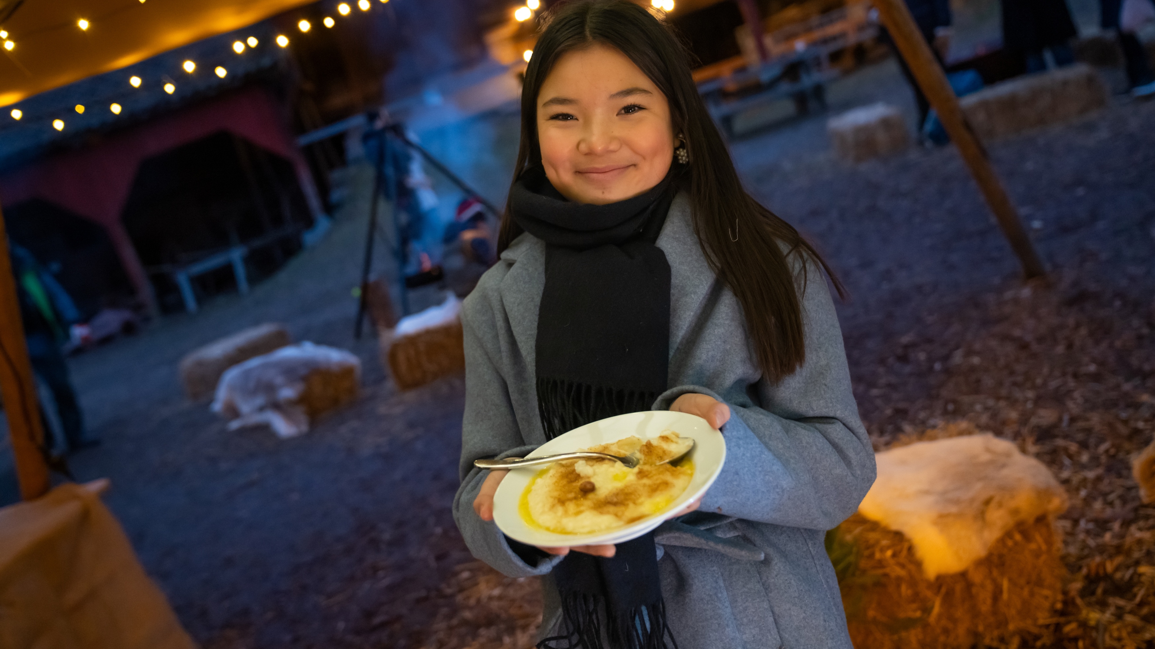 A girl is eating porridge at the Christmas market in Norsk Folkemuseum in Bygdøy, Eastern Norway