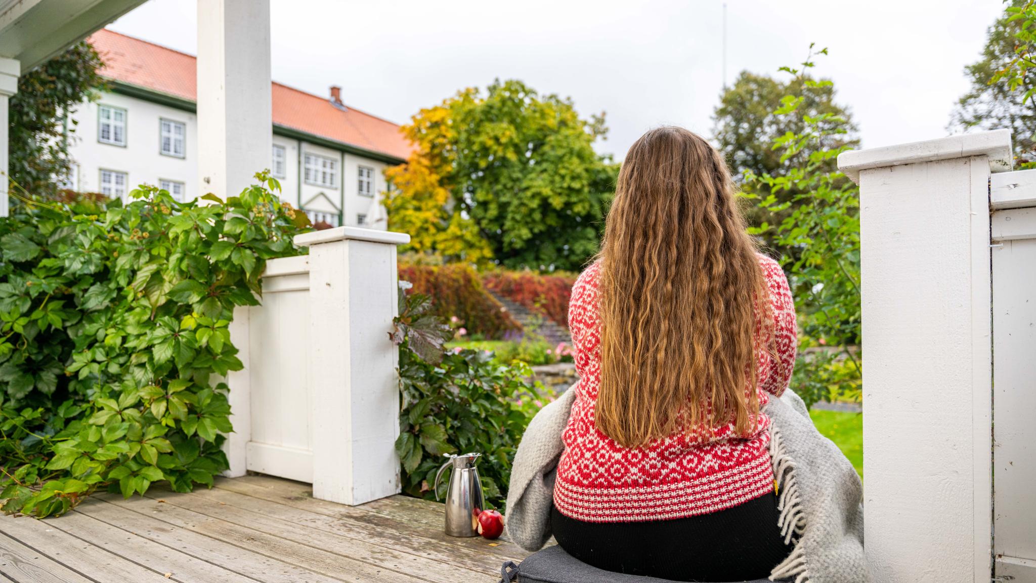 A woman enjoying the view of the garden at the farm Hoel Gård at Nes, Eastern Norway.