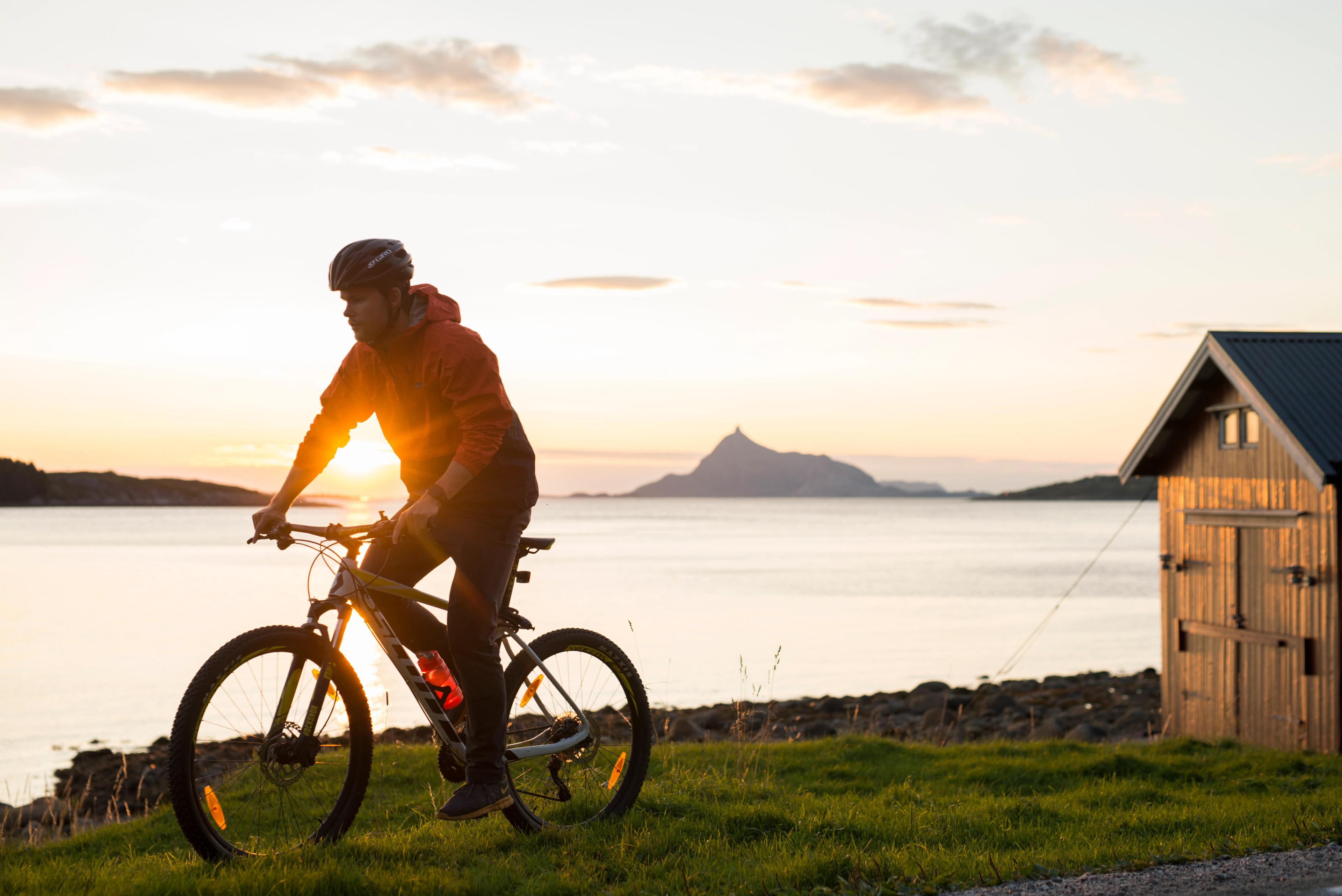 A person cycling in midnight sun on the Lurøy island in Helgeland, Northern Norway