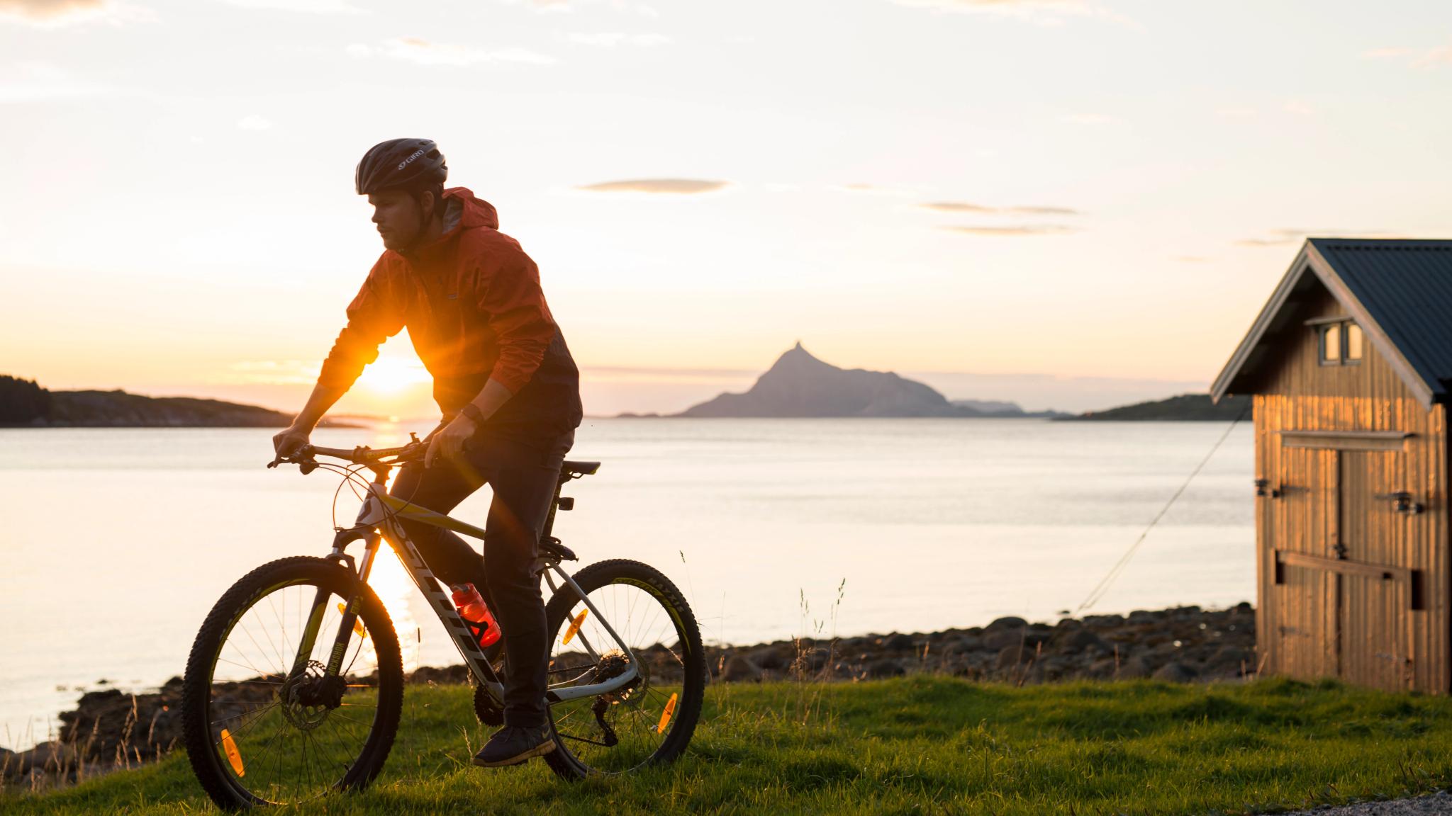 A person cycling in midnight sun on the Lurøy island in Helgeland, Northern Norway