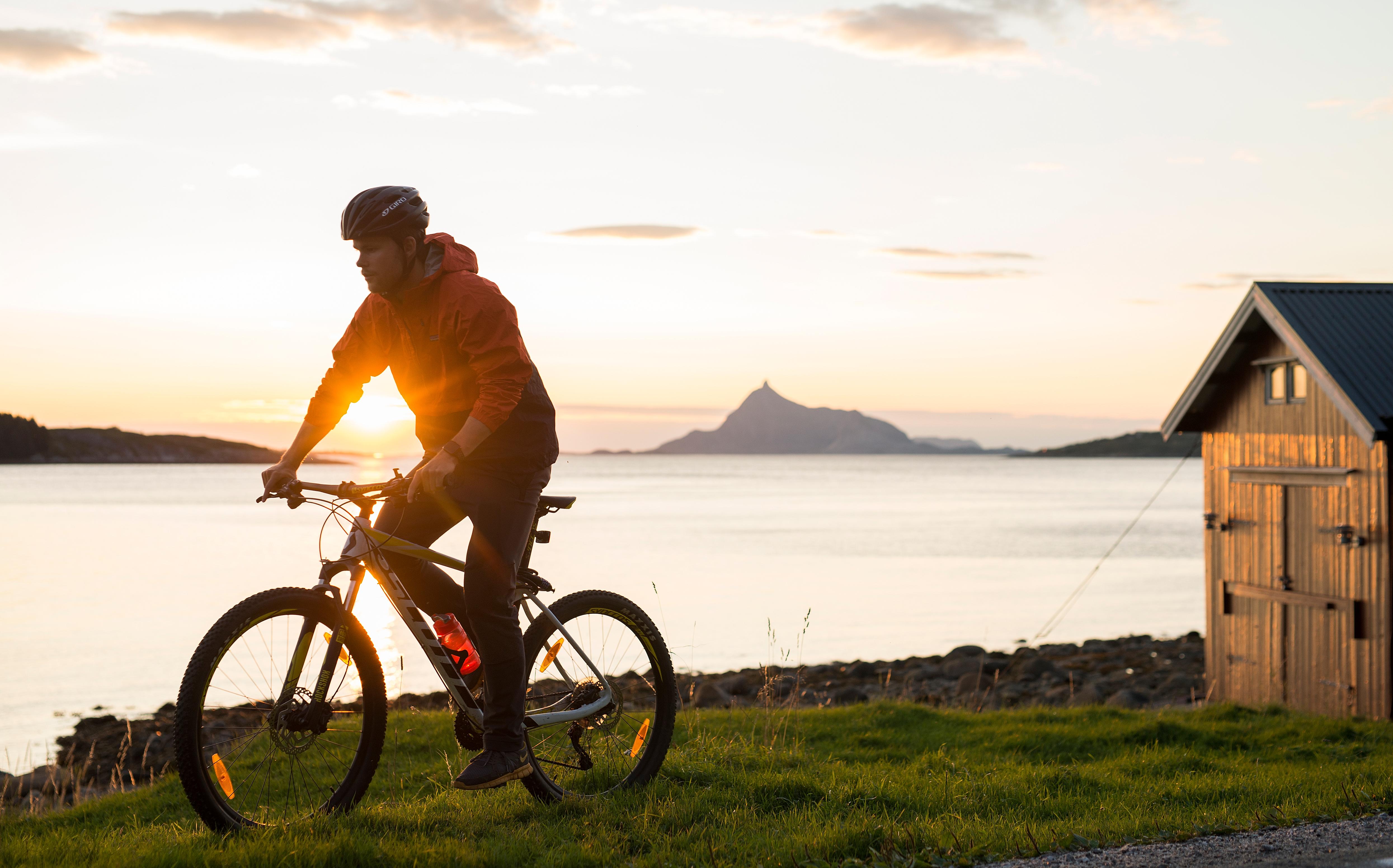 A person cycling in midnight sun on the Lurøy island in Helgeland, Northern Norway