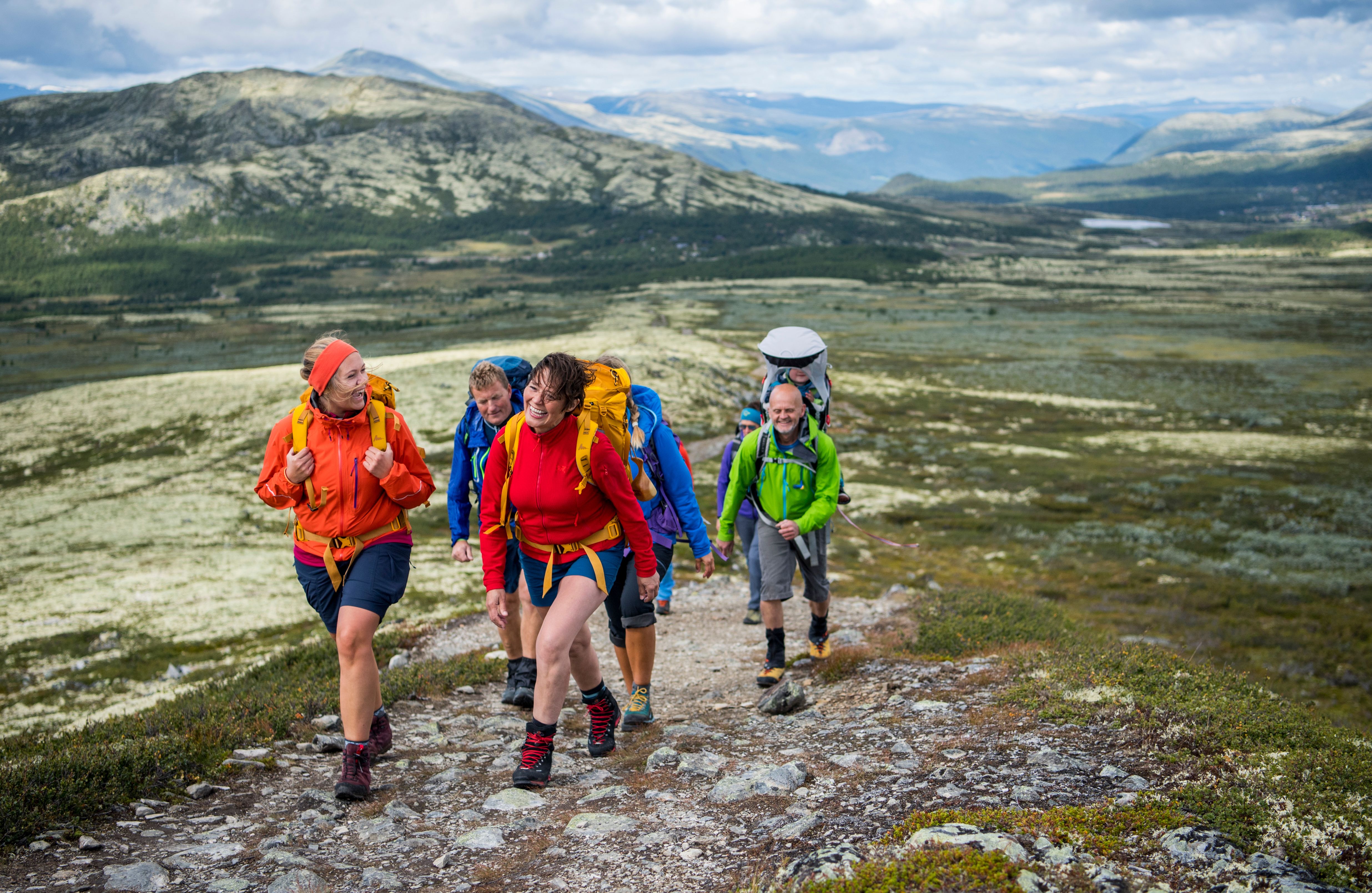 A group of people hiking up Høvringen in Rondane, Eastern Norway, with mountains in the background.