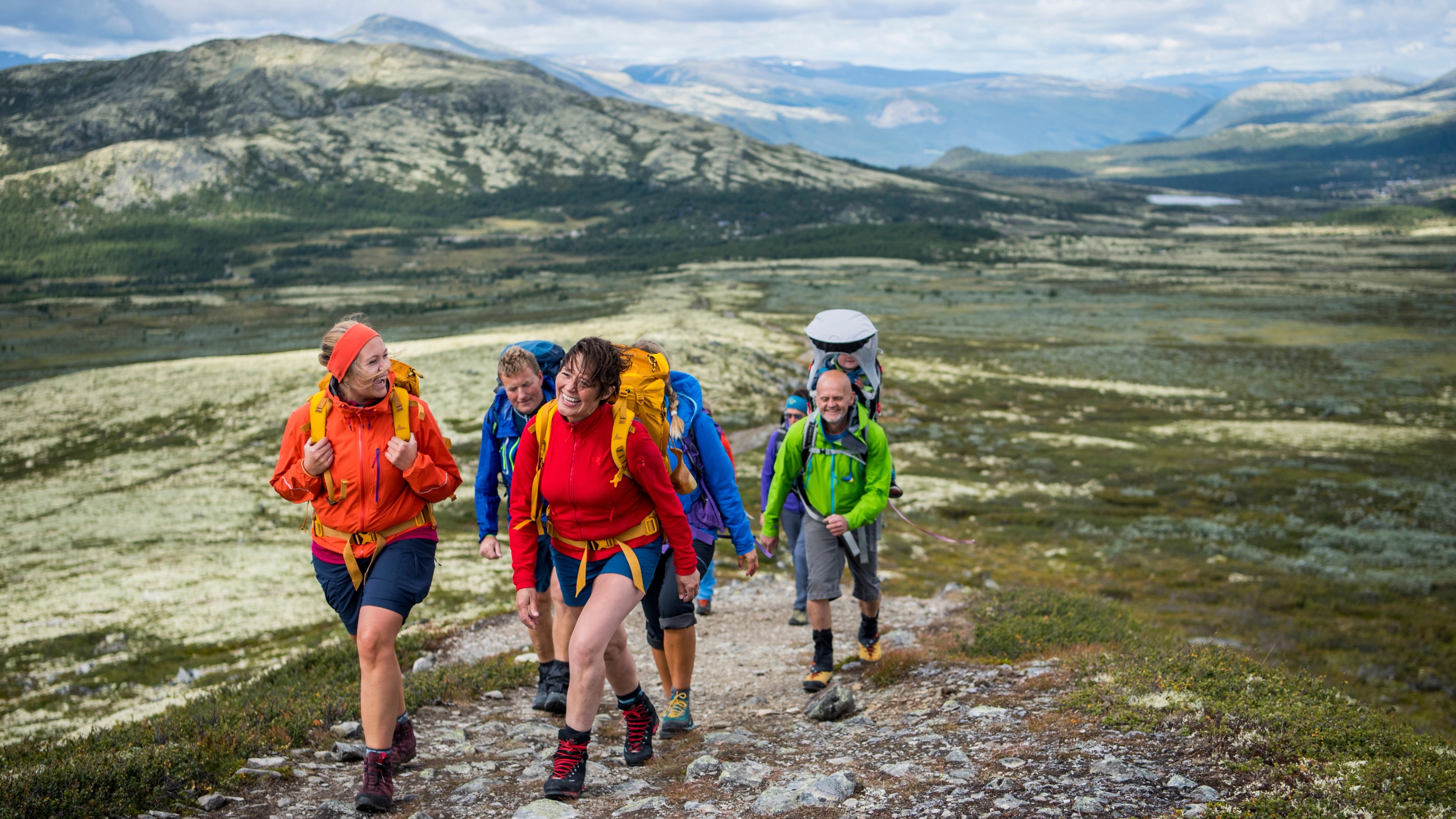 A group of people hiking up Høvringen in Rondane, Eastern Norway, with mountains in the background.