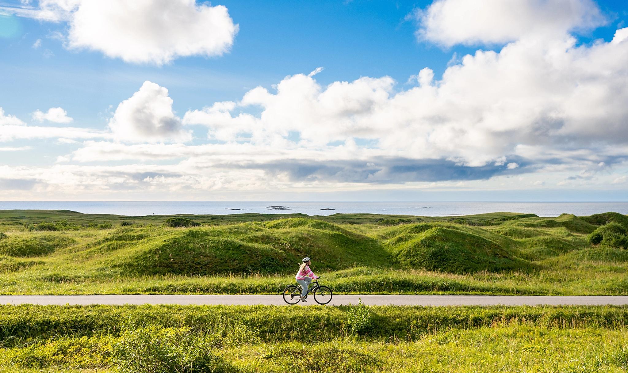 En kvinne sykler på Nasjonal turistveg Andøya