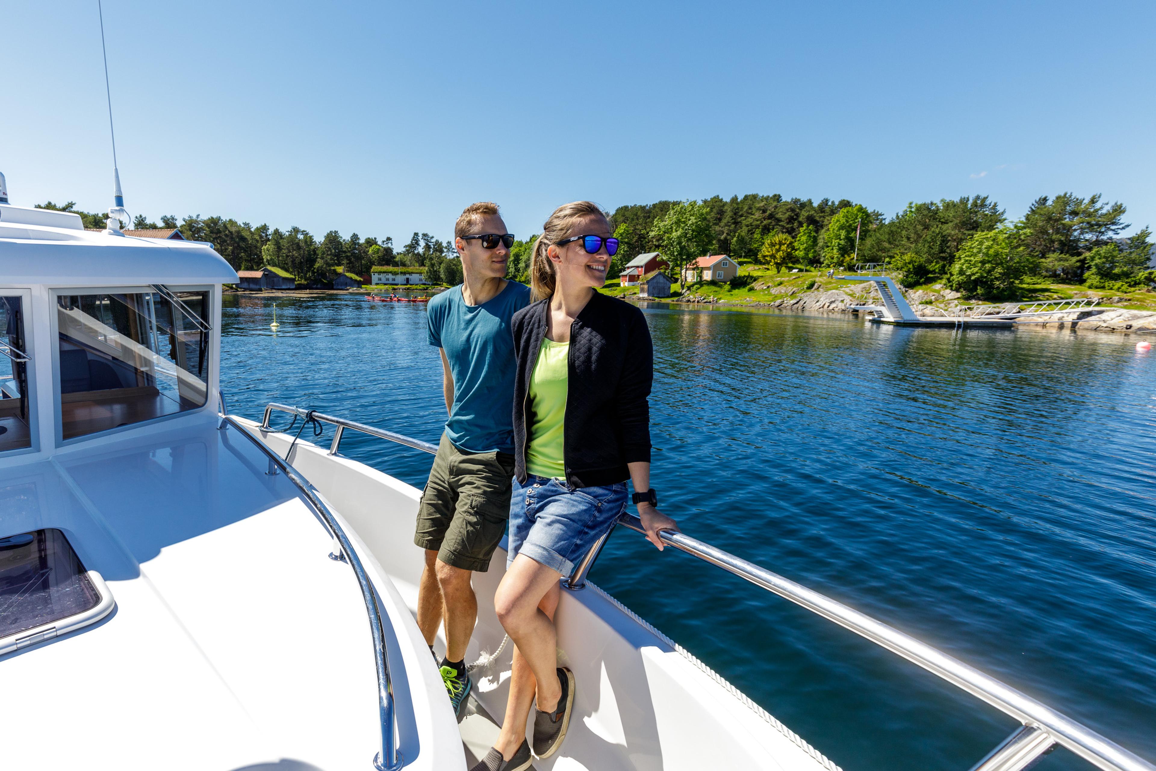 A man and a woman standing on a boat close to Hjertøya in Molde. Northwest, Fjord Norway.