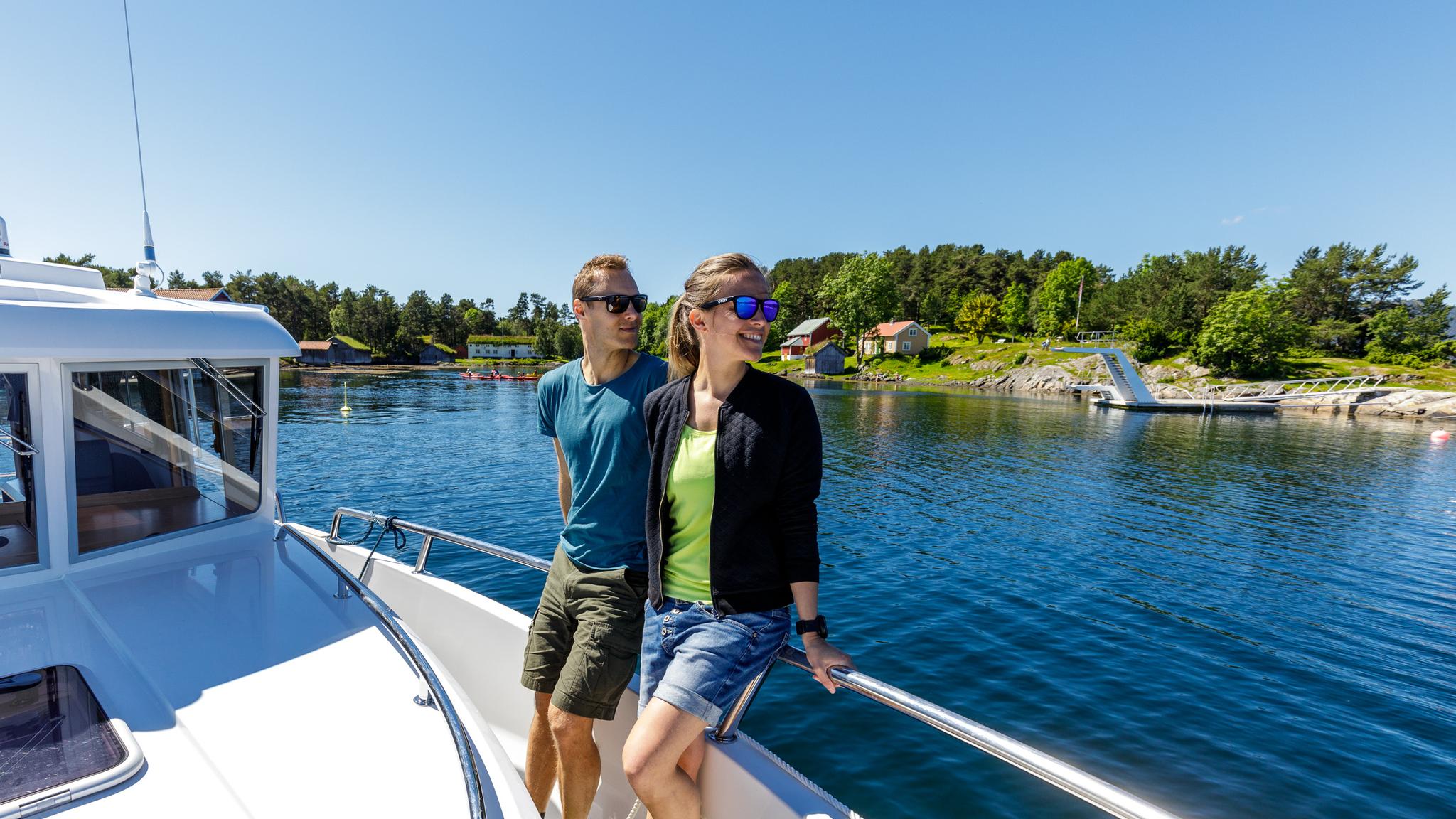 A man and a woman standing on a boat close to Hjertøya in Molde. Northwest, Fjord Norway.