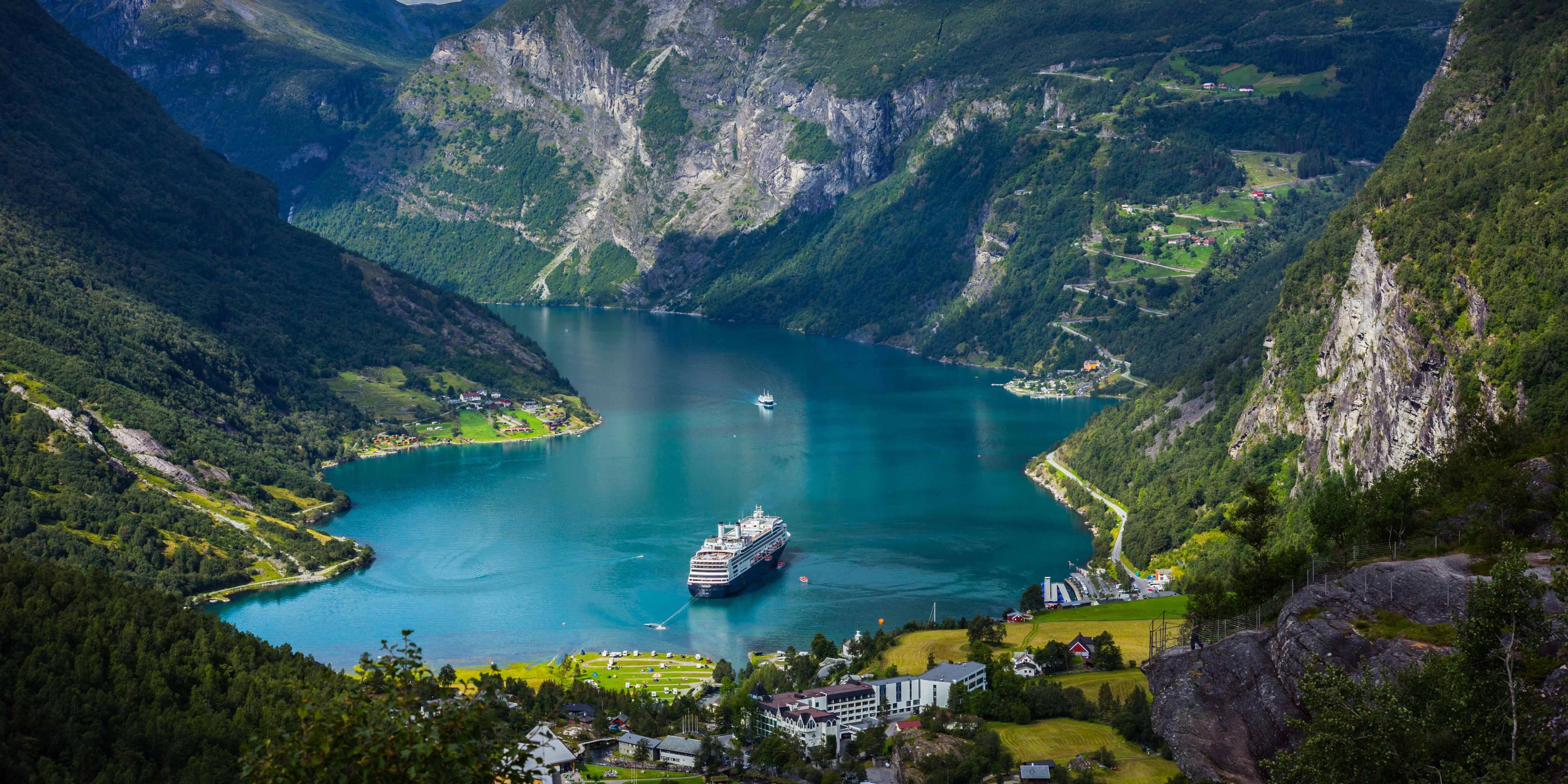 Cruise ship in turquoise fjord waters surrounded by steep mountains