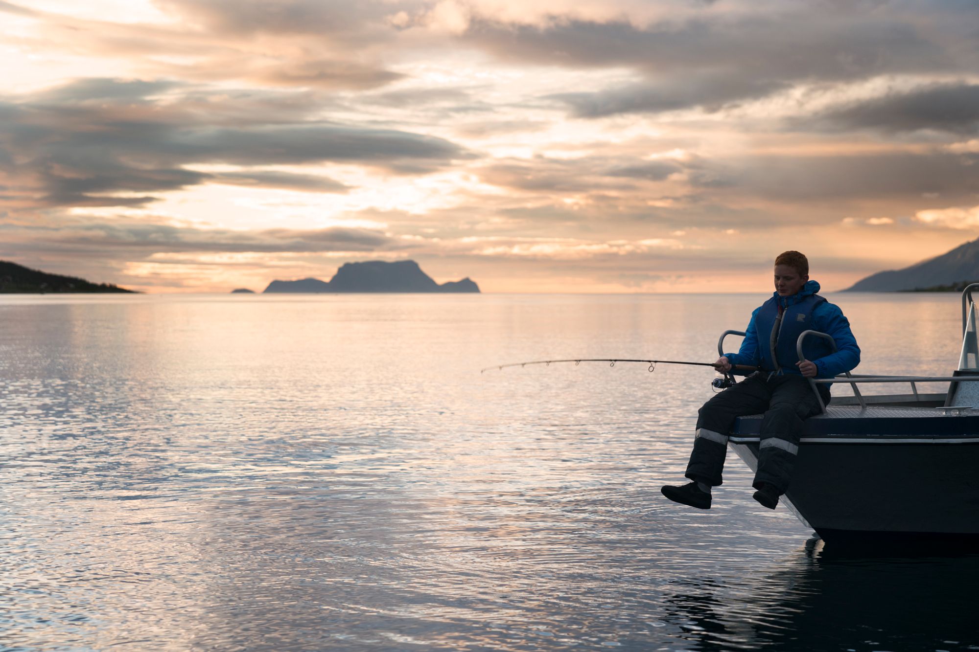 A person fishing under the midnight sun in Lyngen, Northern Norway