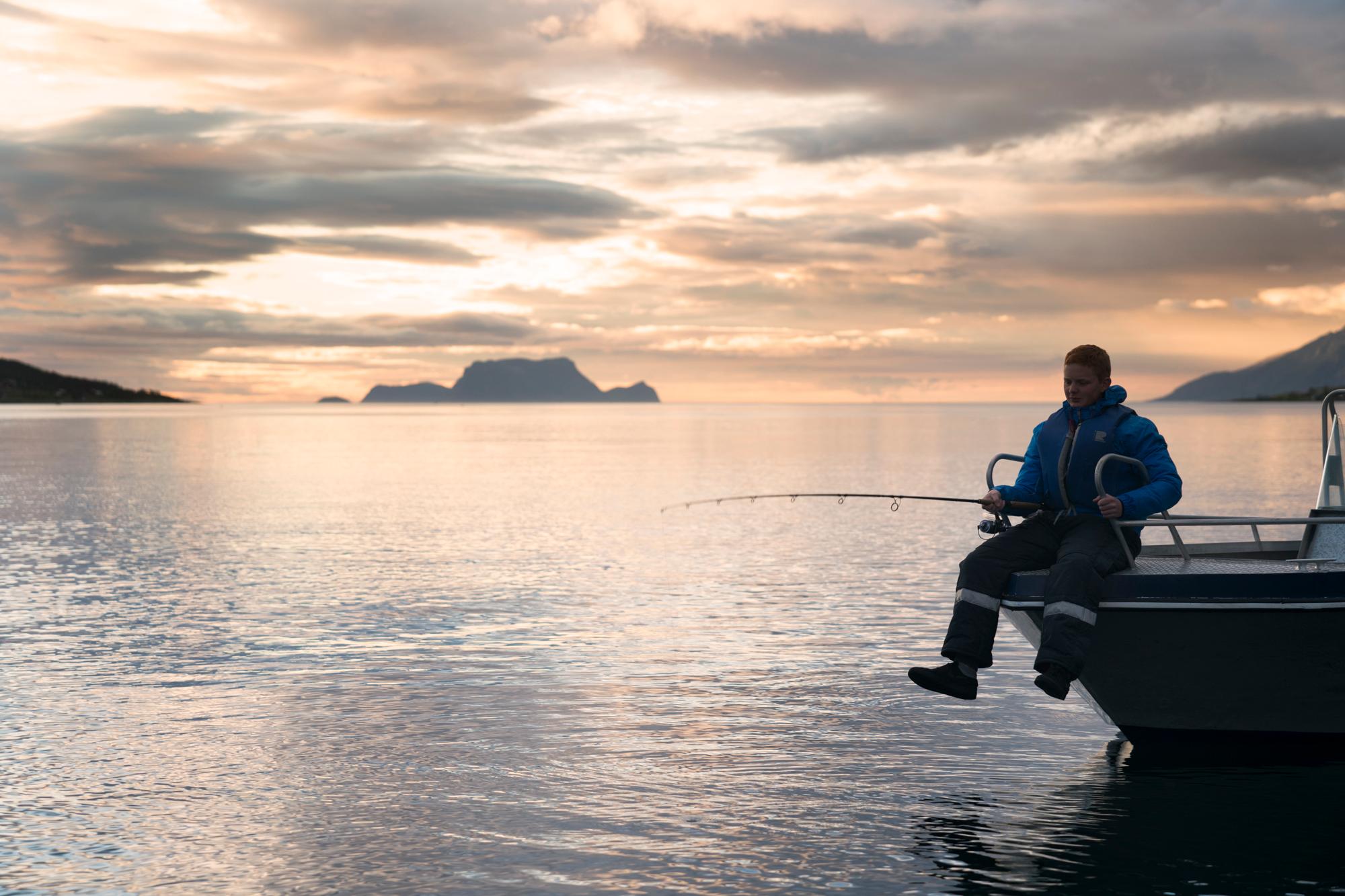 A person fishing under the midnight sun in Lyngen, Northern Norway