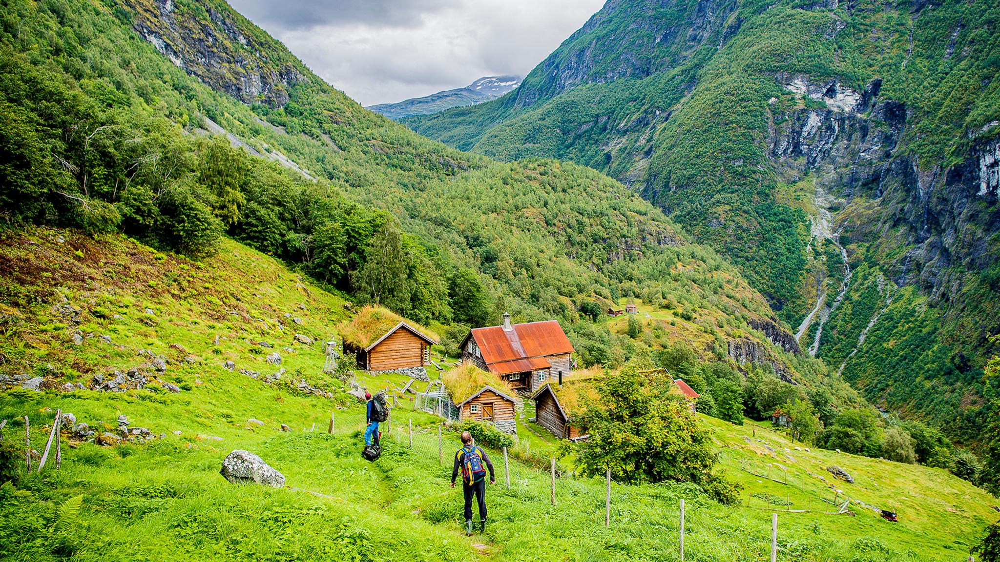 Två personer går mot fjällgården Avdalen i Utladalen, Fjord Norge