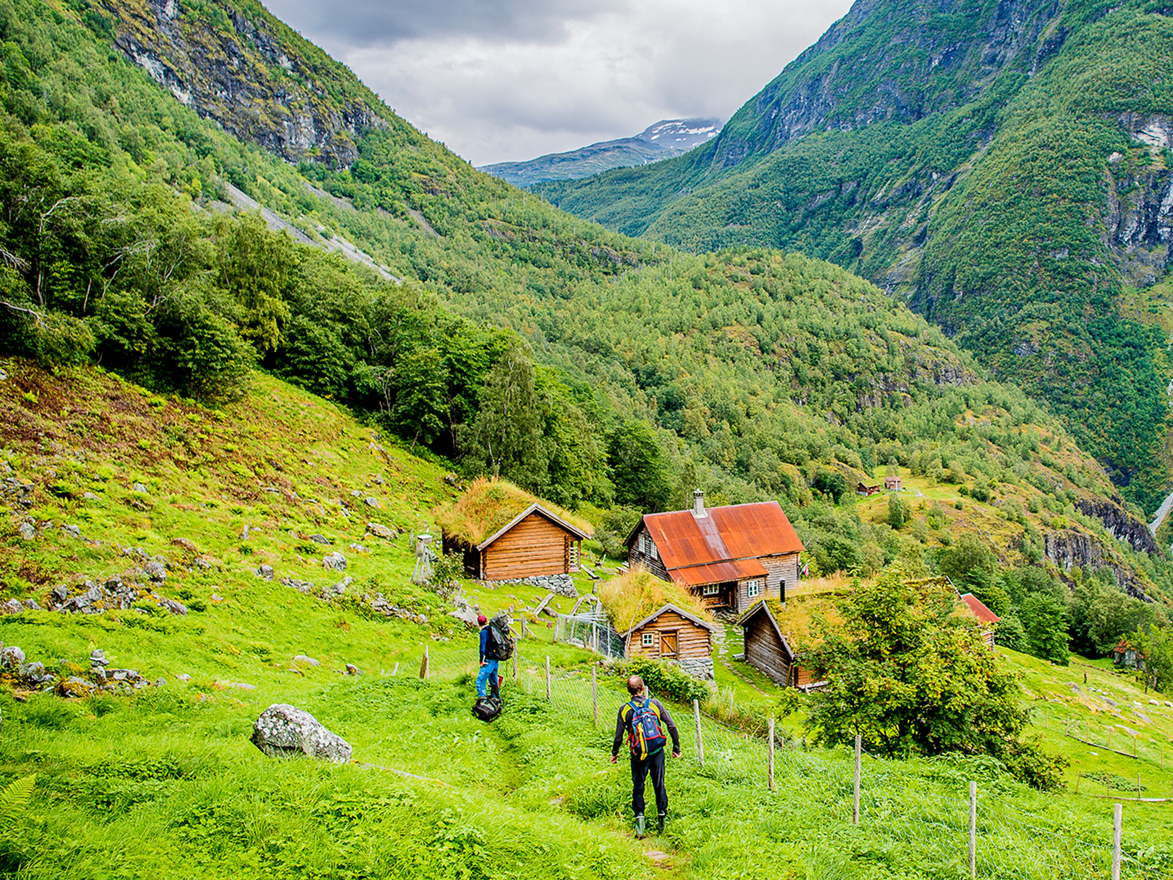 Två personer går mot fjällgården Avdalen i Utladalen, Fjord Norge
