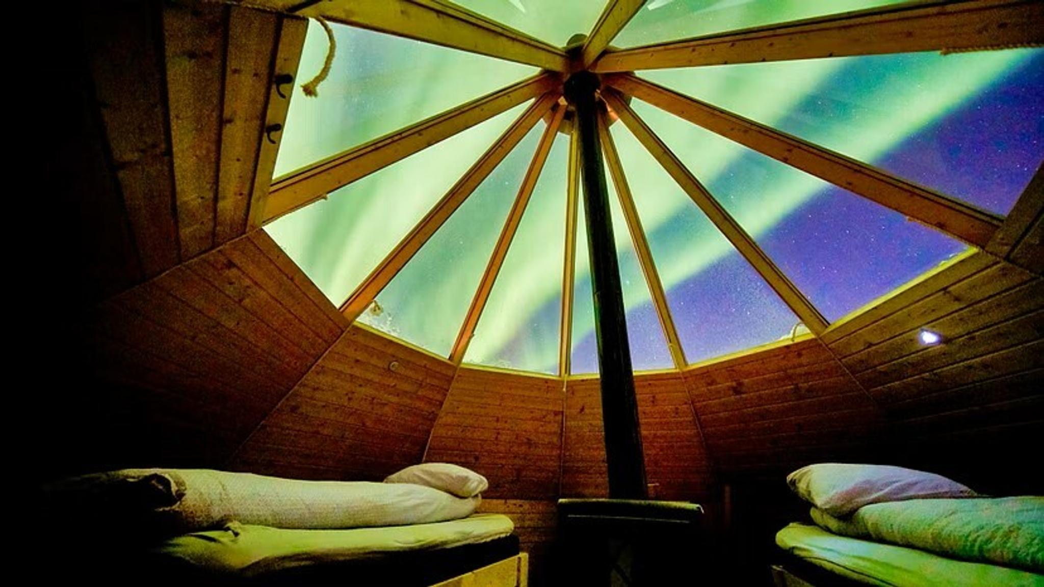 Crystal lavvo interior: beds under northern lights and stargazing dome.