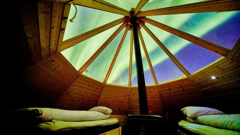 Crystal lavvo interior: beds under northern lights and stargazing dome.