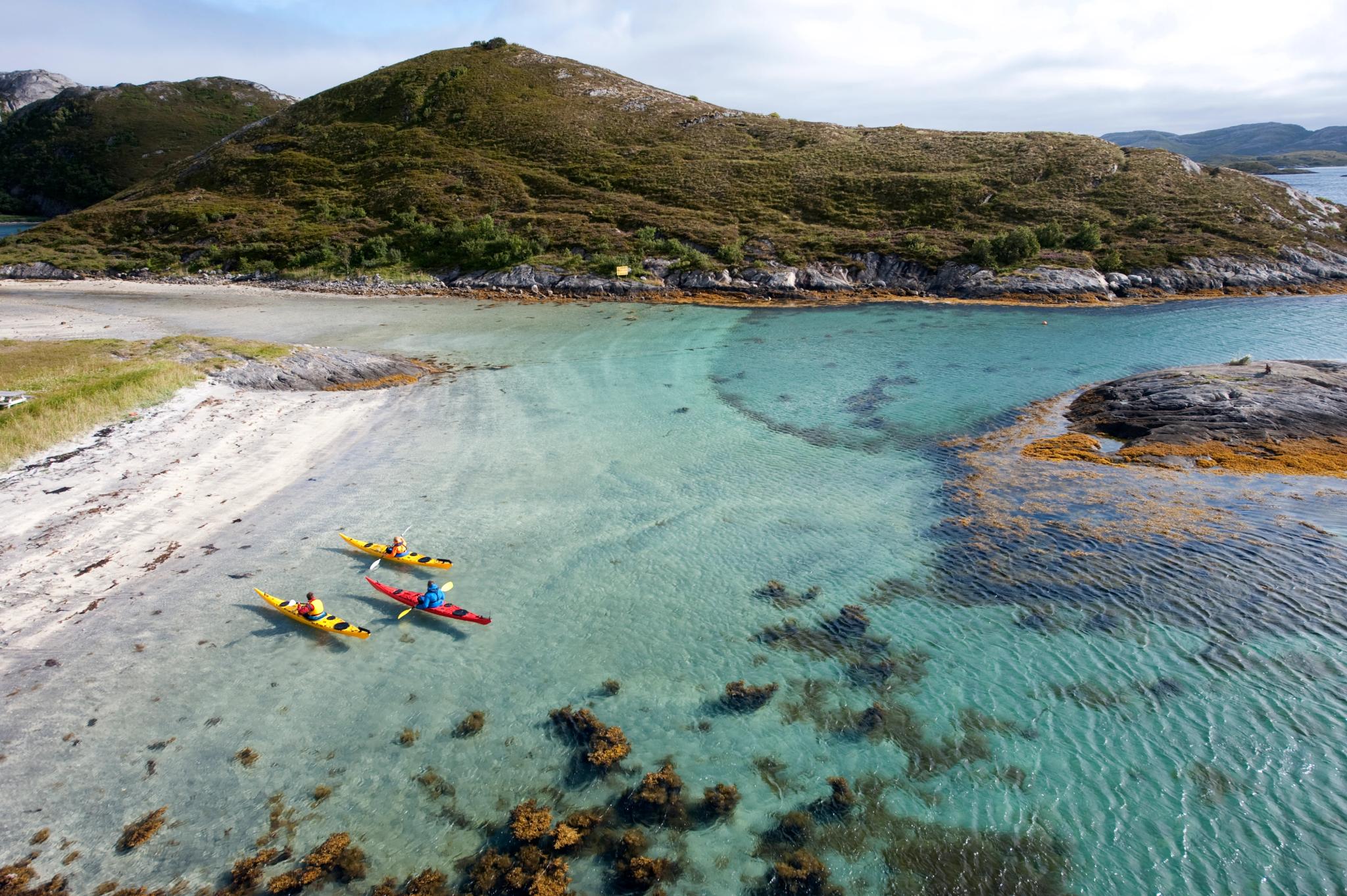 Three kayakers paddling around Rødøy in Helgeland, Northern Norway
