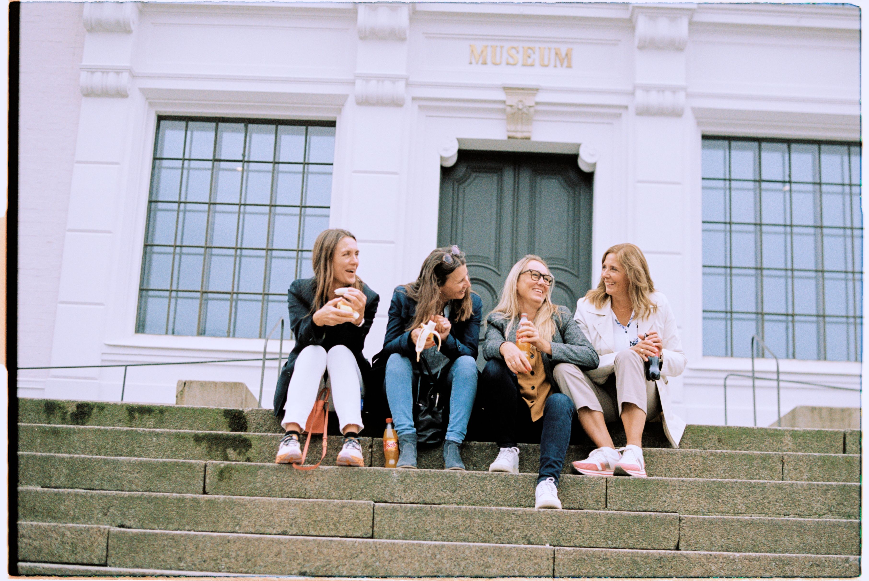 Four menopausal women sitting in stairs in front of museum in Bergen