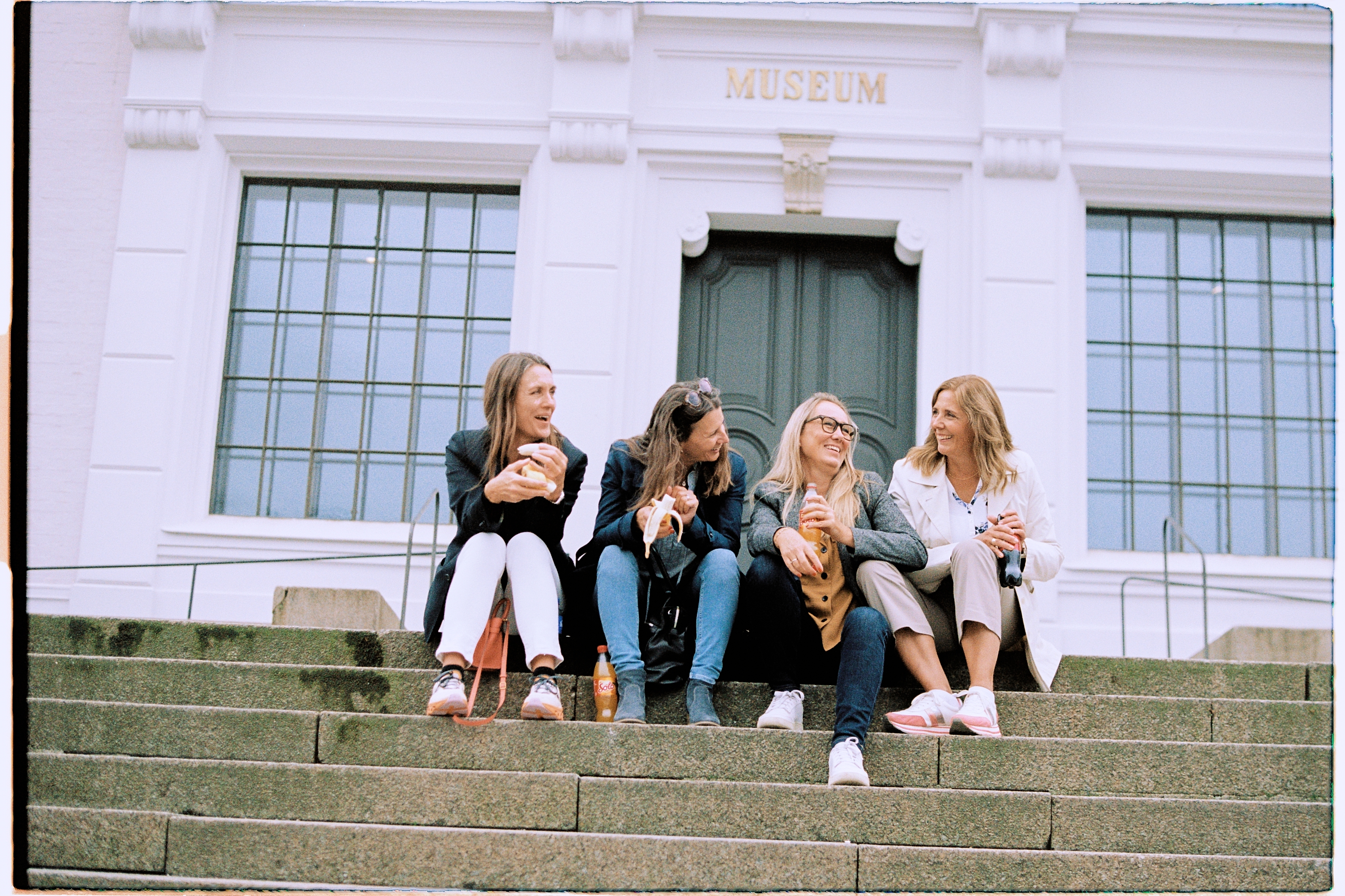 Four menopausal women sitting in stairs in front of museum in Bergen