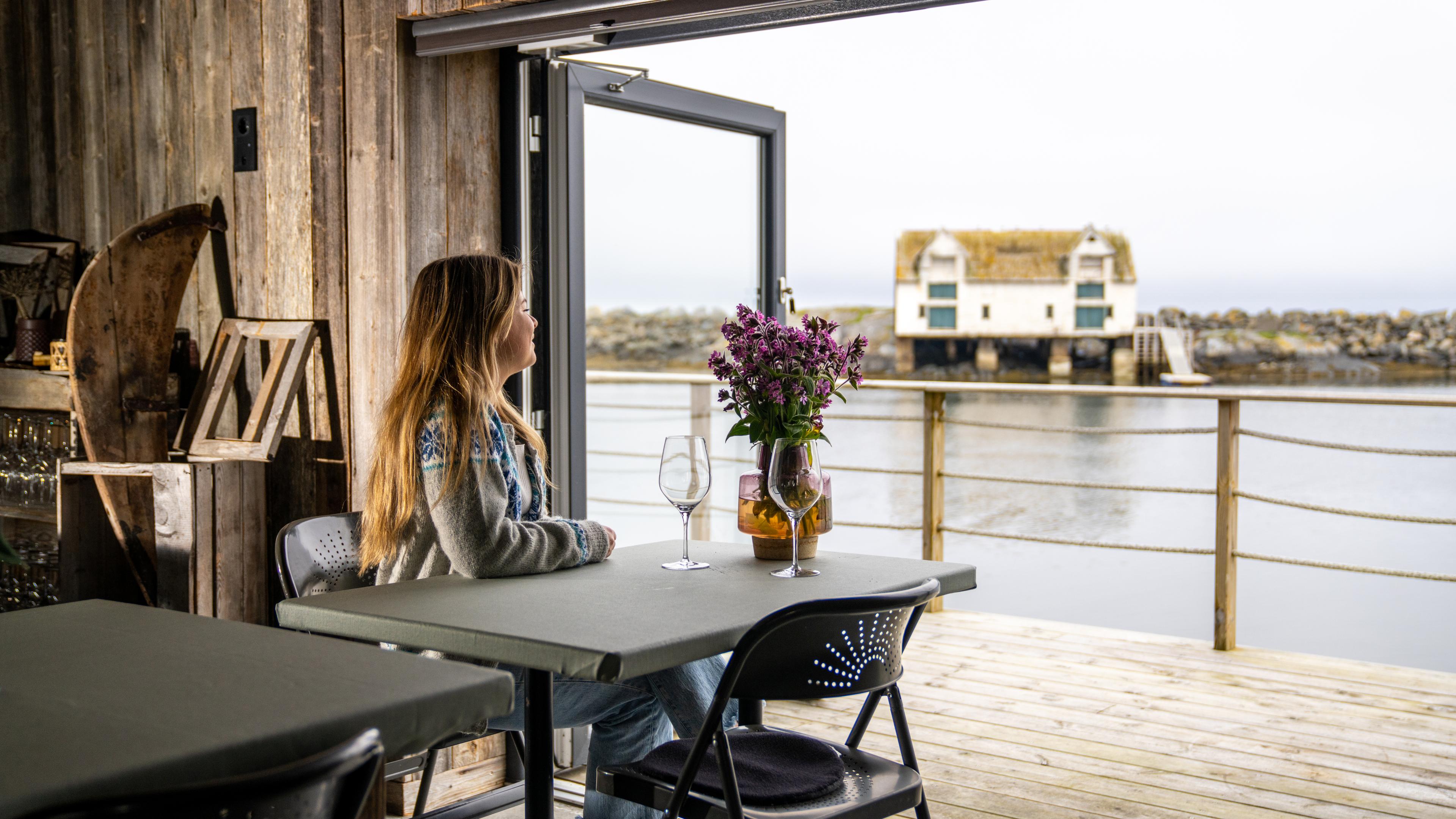 A woman enjoying the view from the restaurant at OlsenNaustet, Veiholmen