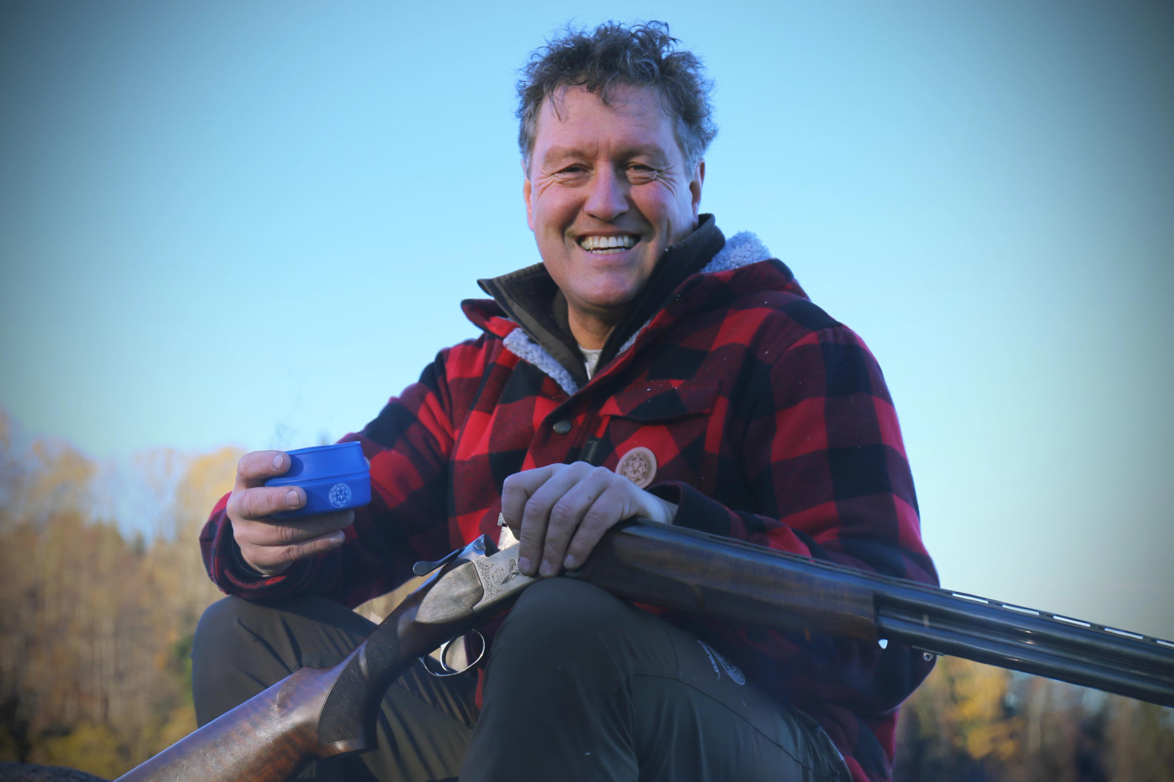 Espen Farstad sitter ute med en kaffekopp i hånden og riflen sin i fanget
