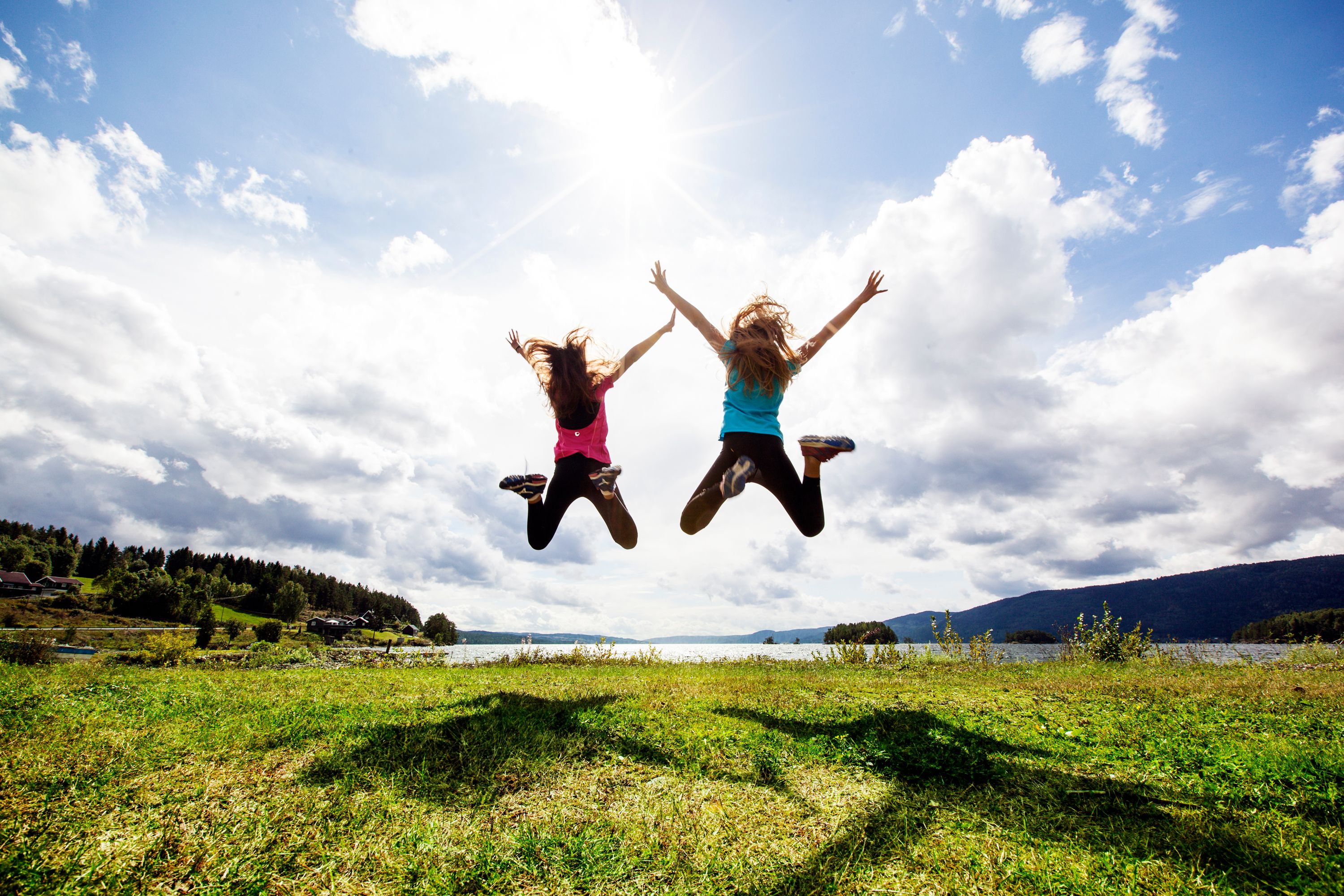 Two girls jumping in the air by Randsfjorden
