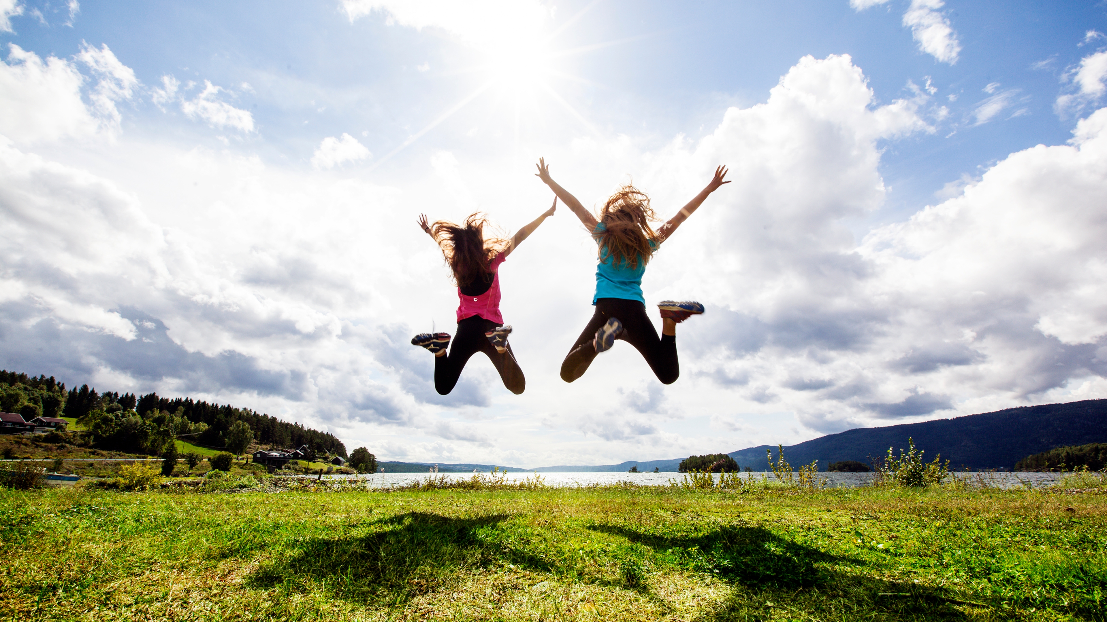 Two girls jumping in the air by Randsfjorden