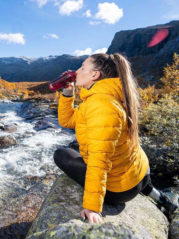Woman drinking water from a river, Hemsedal, Norway.