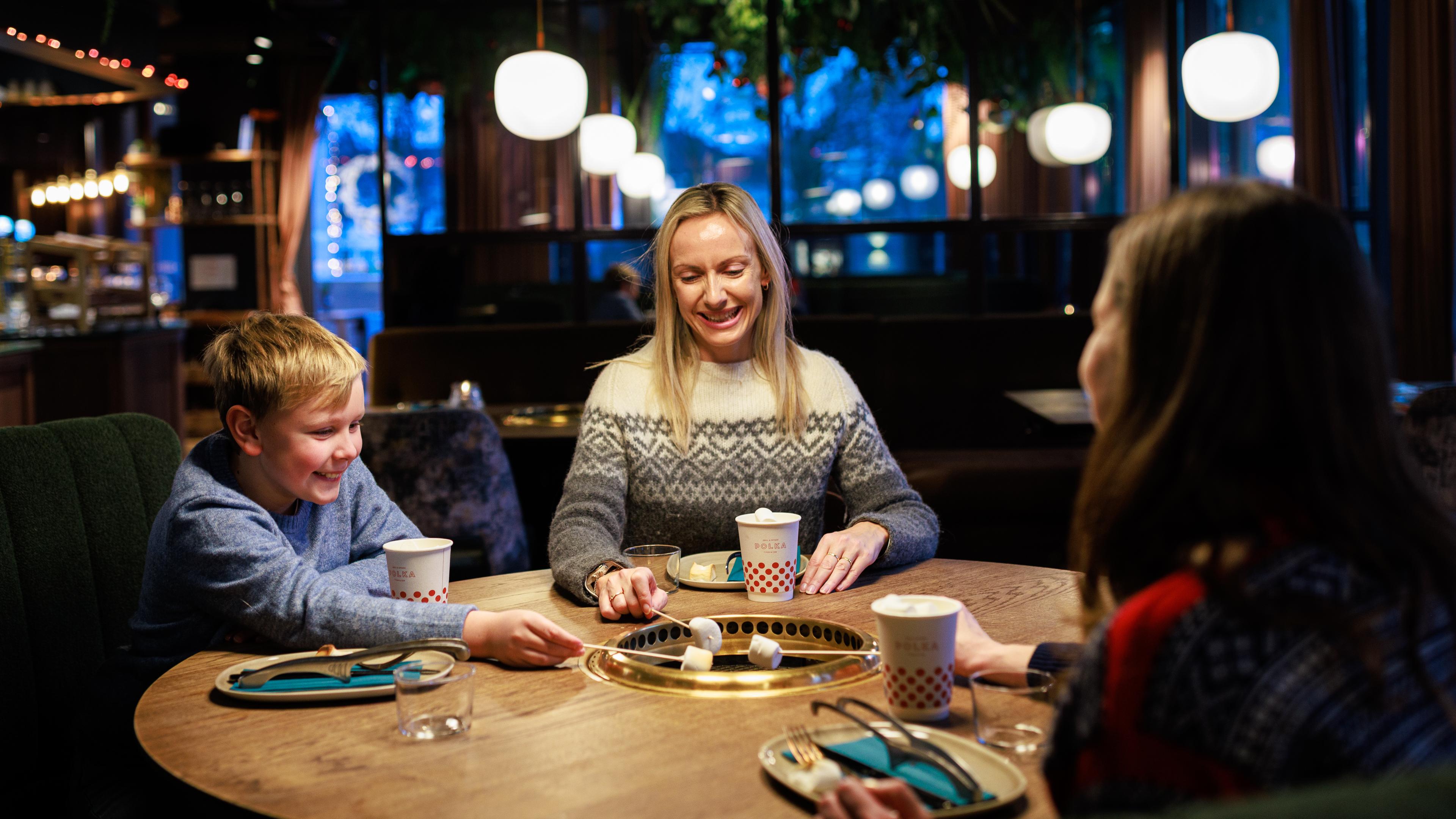 Two woman and a boy grilling marshmellow at the restaurant POLKA Grill & Spiseri in Stavanger