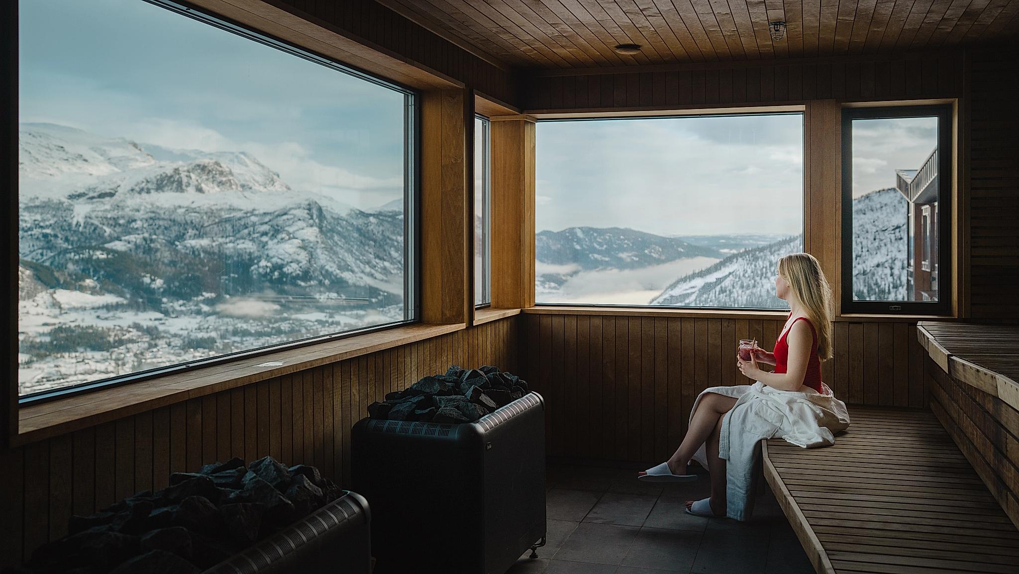 A woman enjoying a mountain view from inside a sauna.