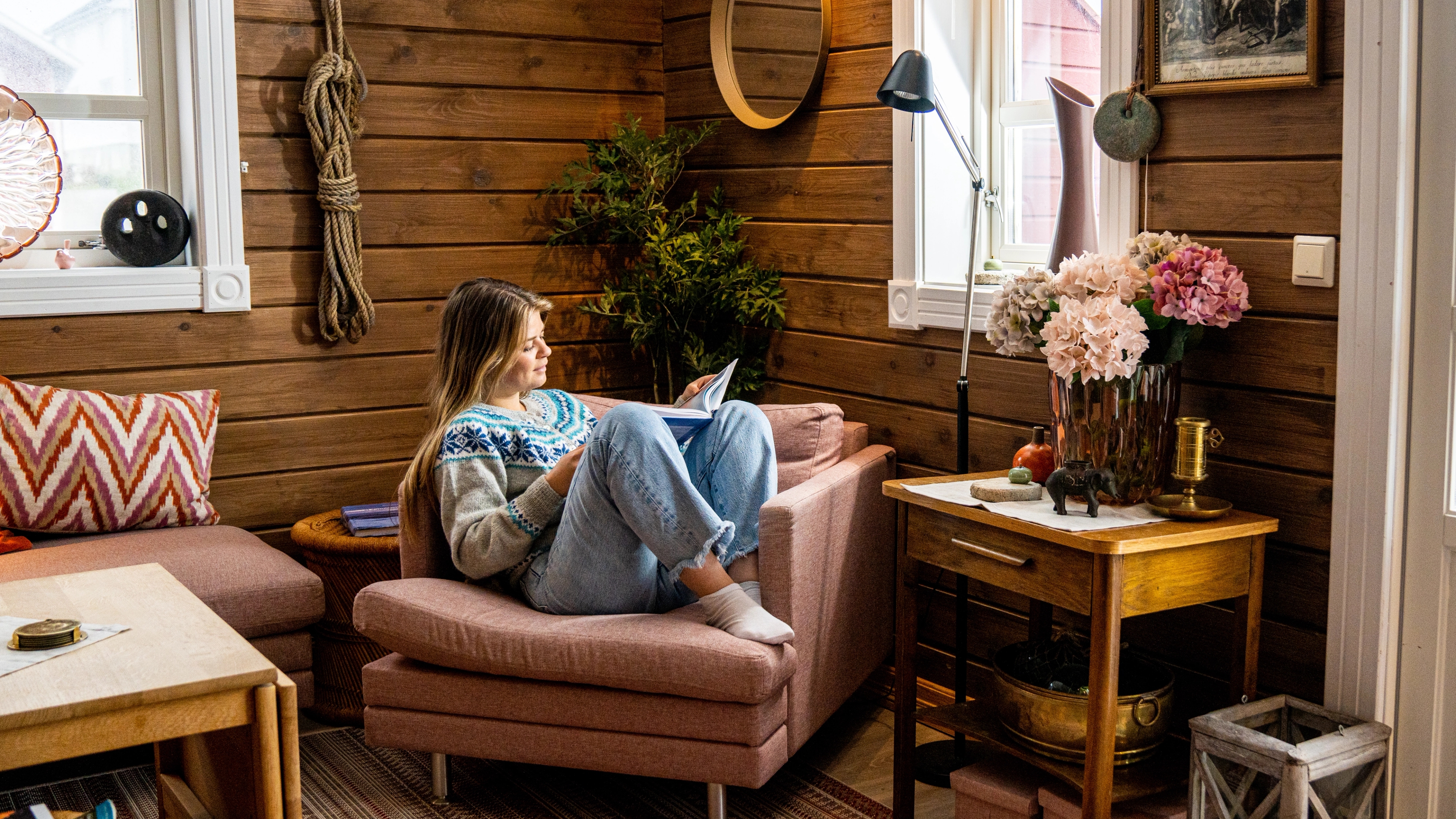 A woman reading a book in a fisherman's cabin by the sea, at Veiholmen outside Smøla in the Northwest