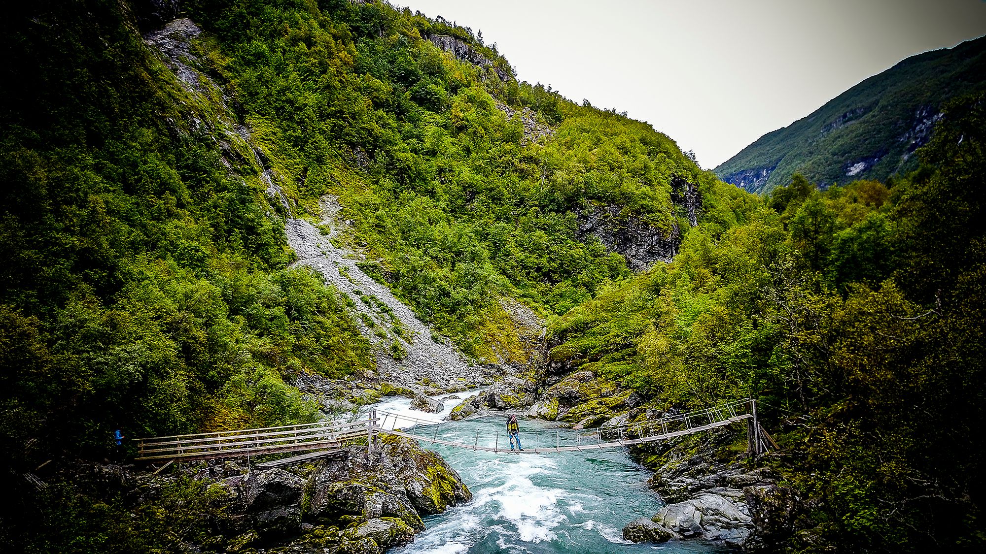 Imagen de una persona cruzando un puente sobre el río en el valle de Utladalen, en la Noruega de los fiordos.
