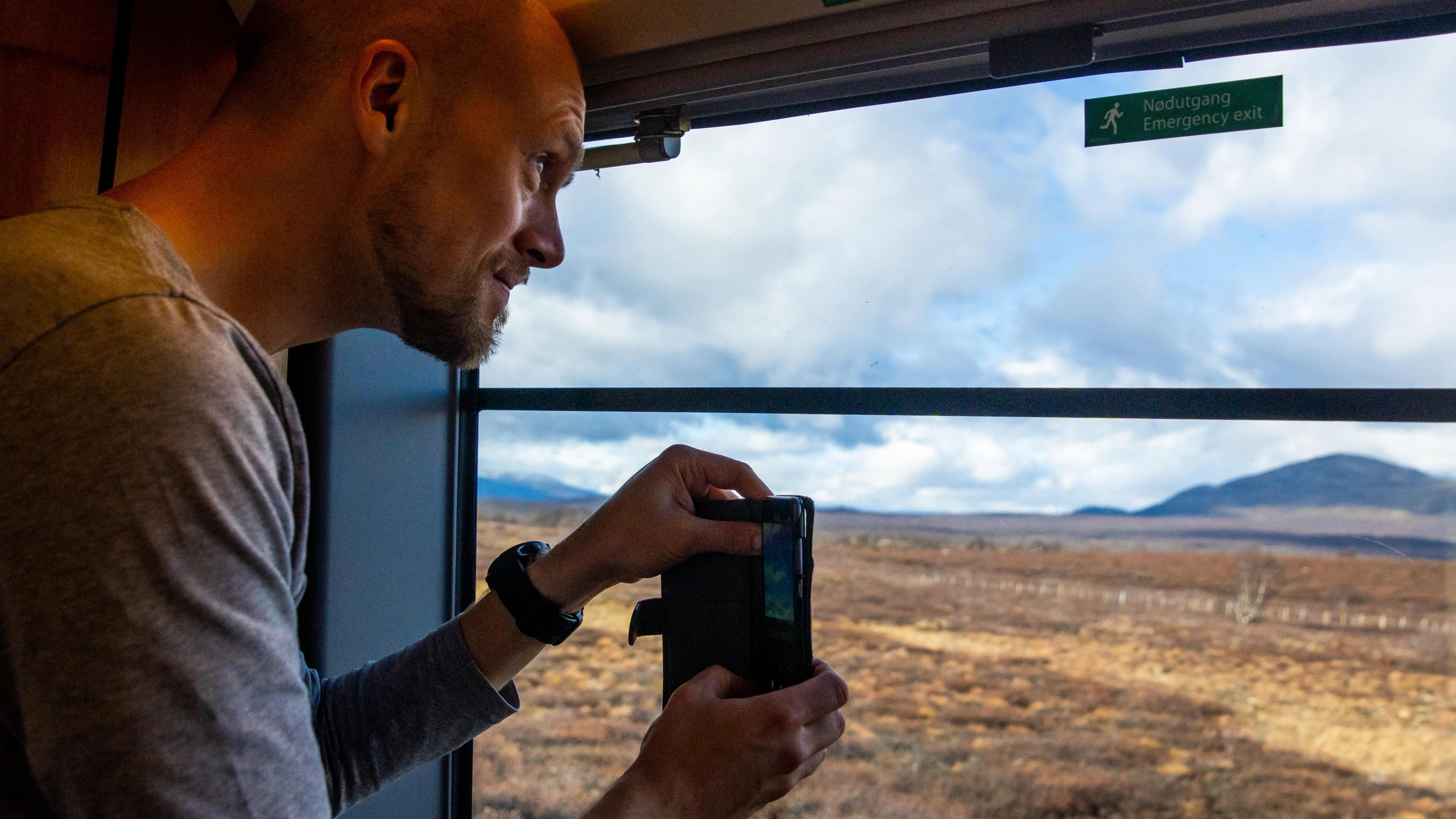 A man taking a photo through the window at the Dovre Railway