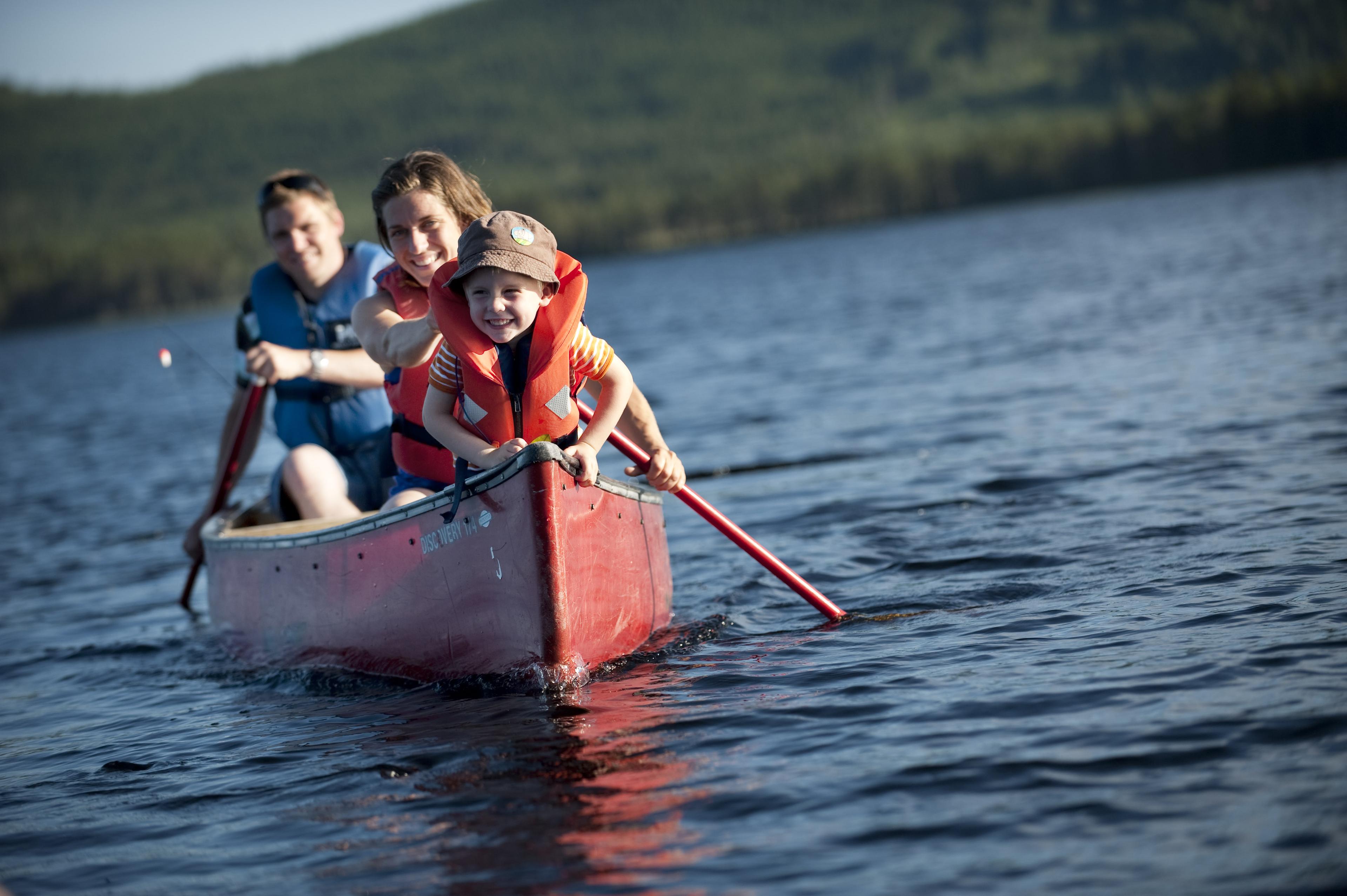 Family canoeing on the river in Trysil, Eastern Norway