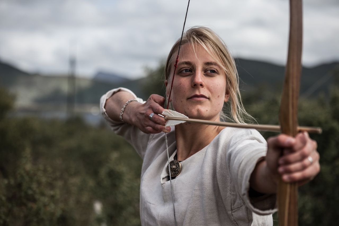 Woman shooting with a bow and arrow at the Lofotr Viking Museum