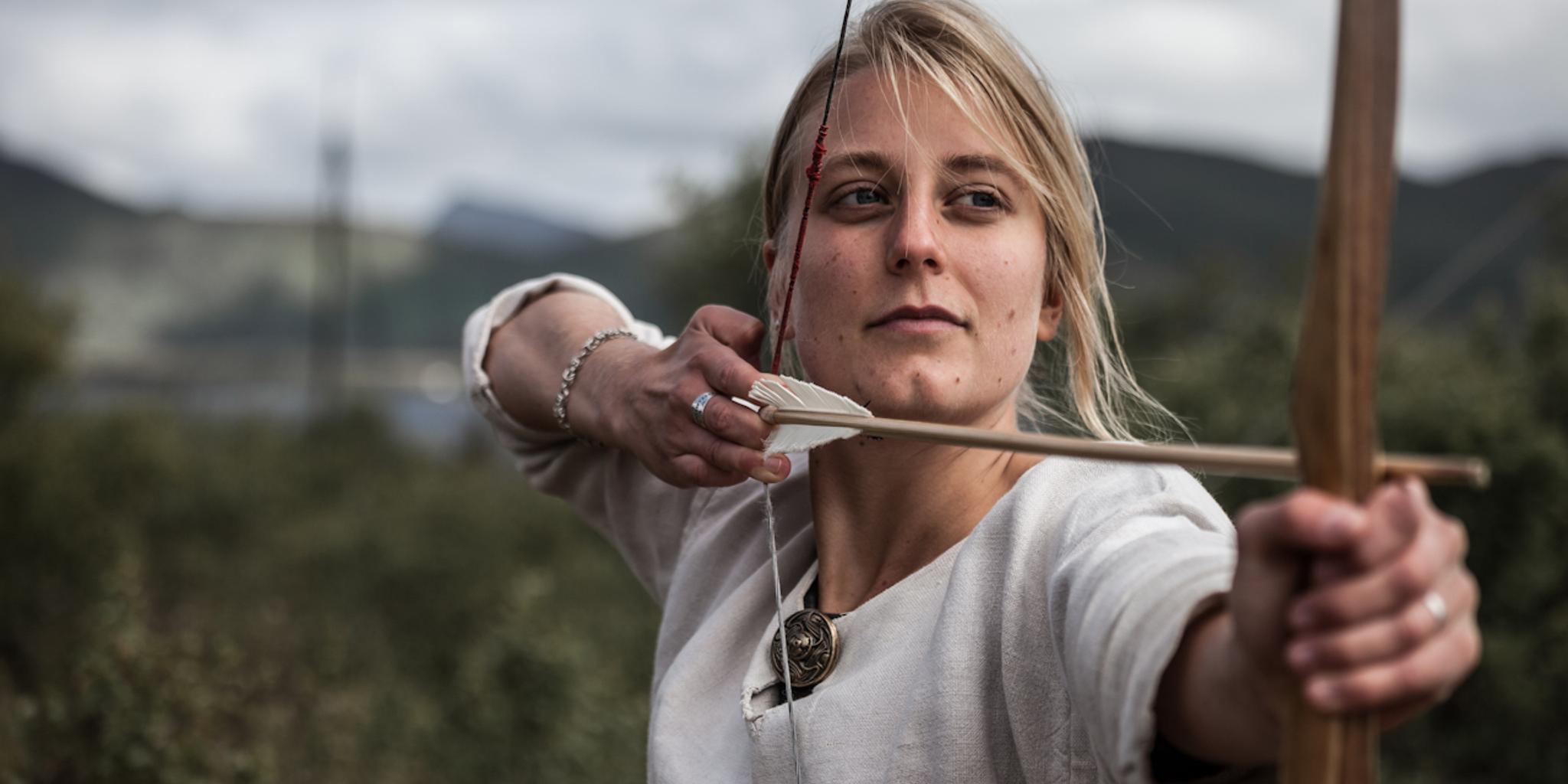 Woman shooting with a bow and arrow at the Lofotr Viking Museum