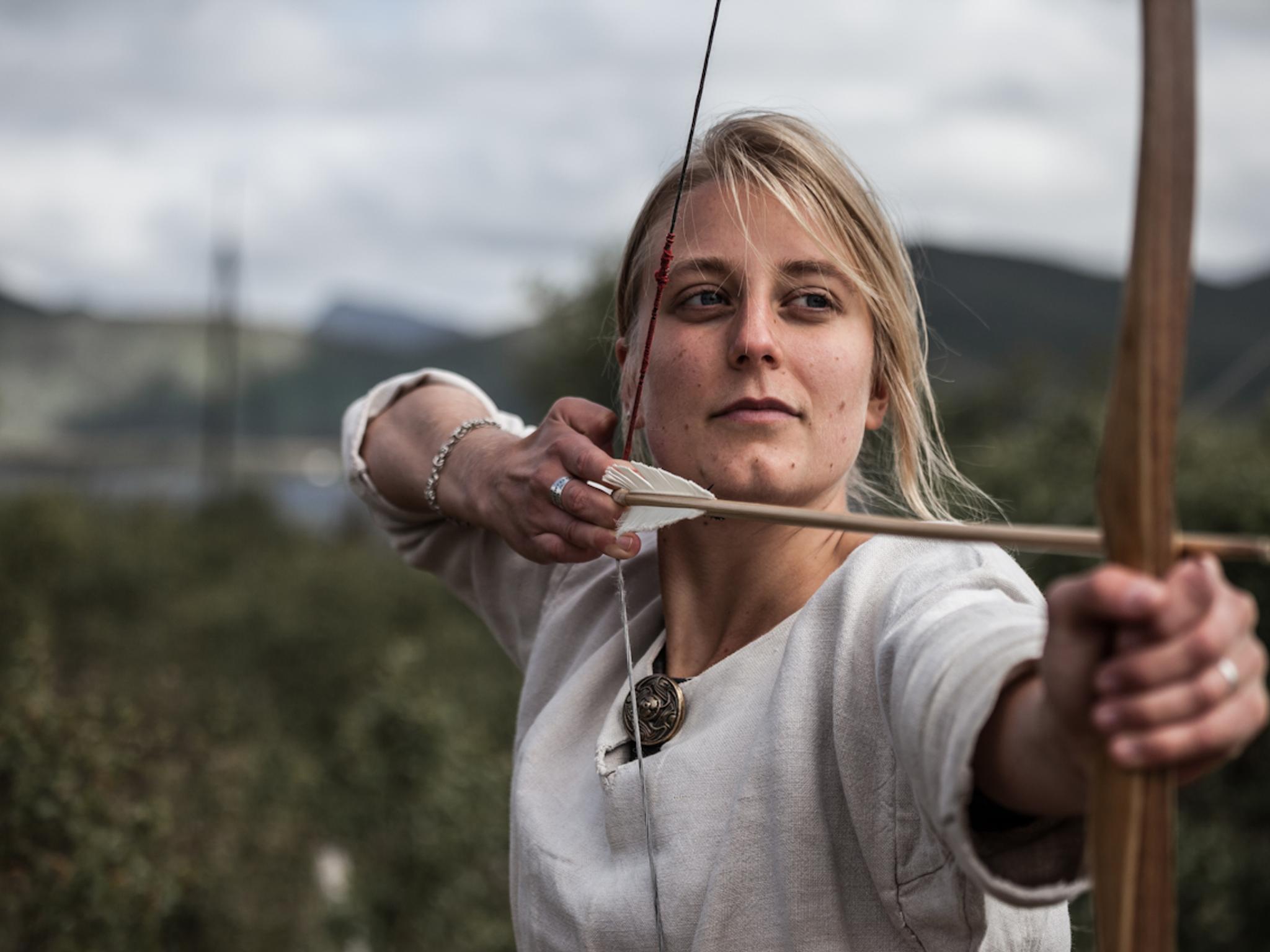 Woman shooting with a bow and arrow at the Lofotr Viking Museum