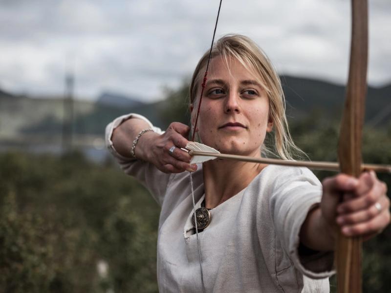 Woman shooting with a bow and arrow at the Lofotr Viking Museum