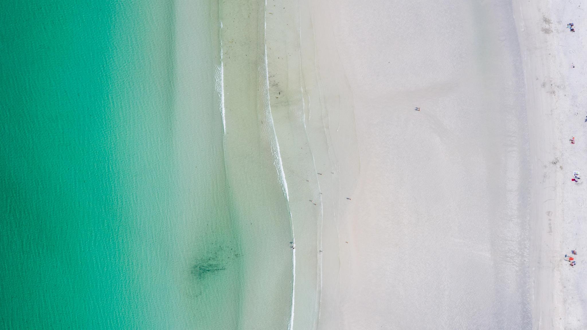 Overview of a sandy beach with clear blue water